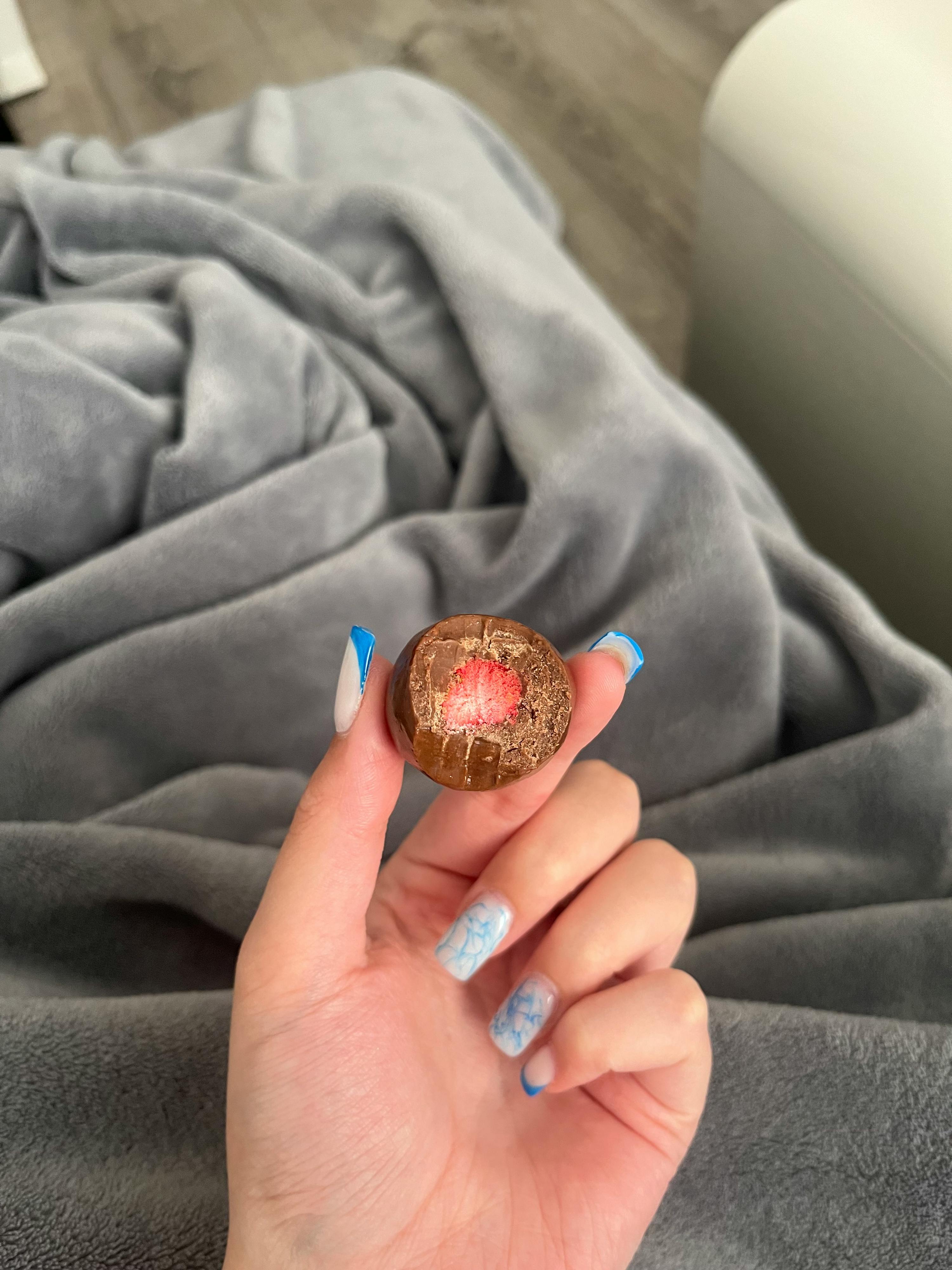 a person holding a chocolate egg with a red center