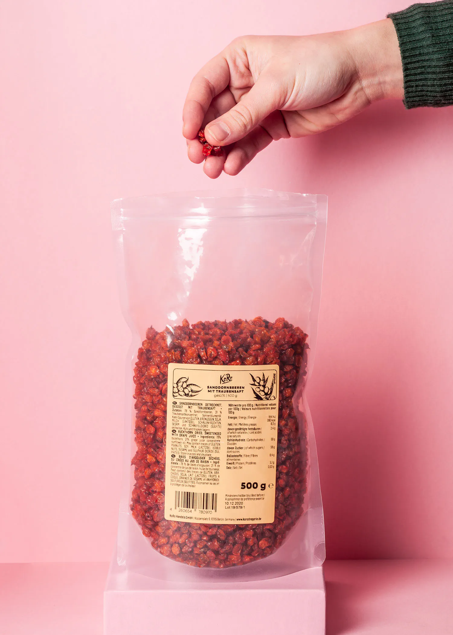 eine Person hält einen Plastikbeutel mit 500 g getrockneten Erdbeeren in der Hand