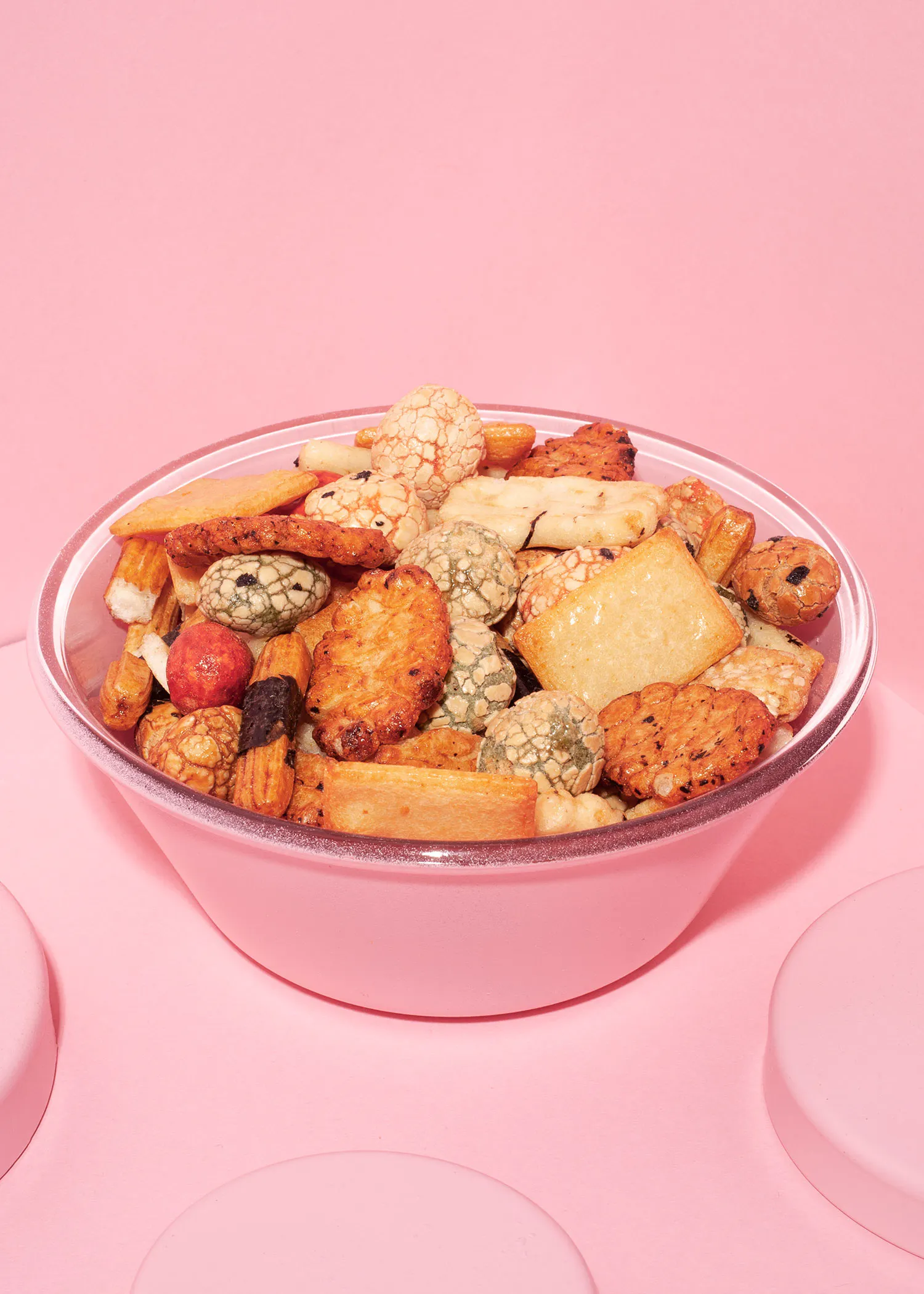 un bol rose rempli de biscuits et de noix sur fond rose