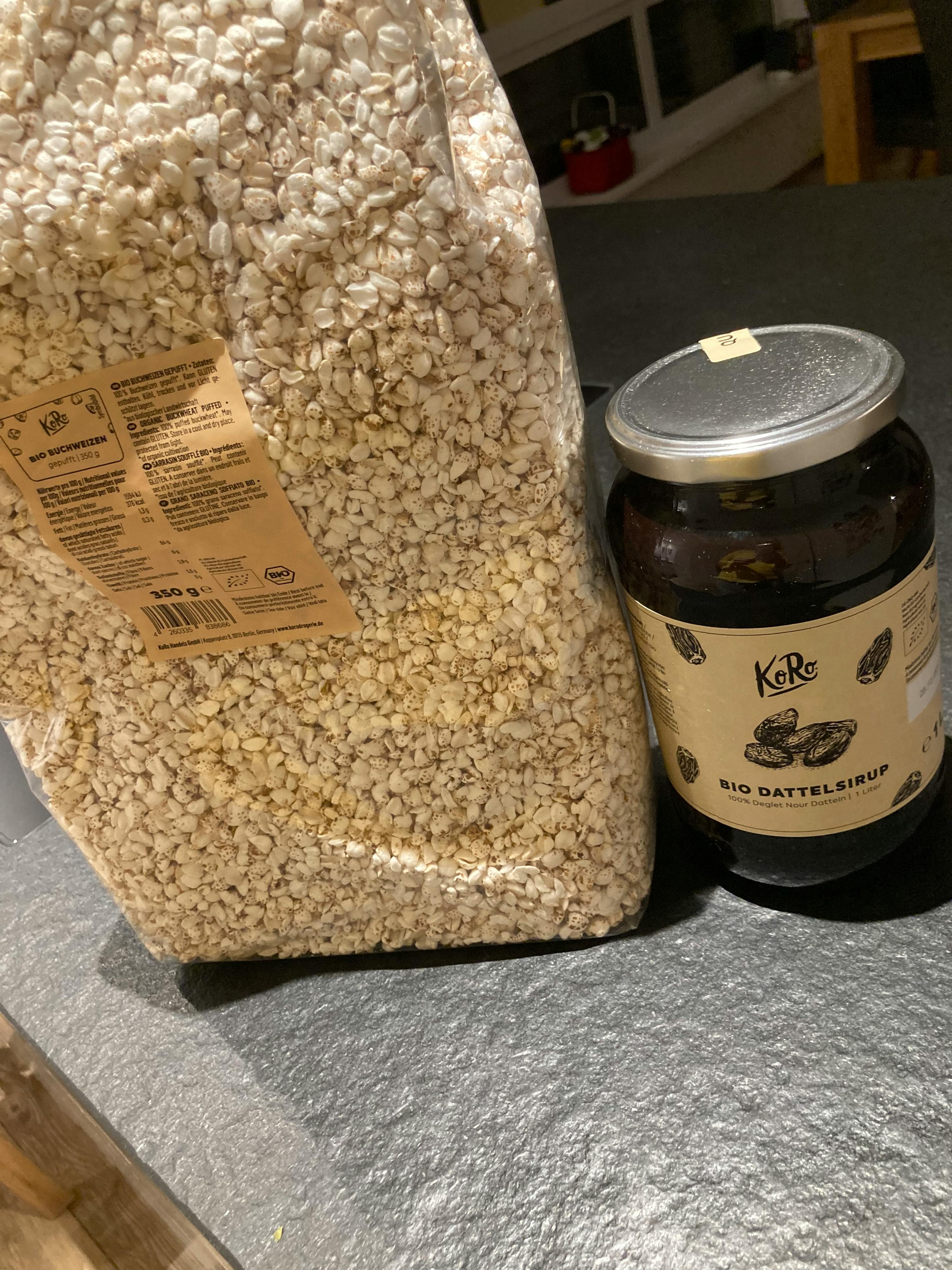 eine Flasche bio dattelsirup steht neben einem großen Haufen Haferflocken