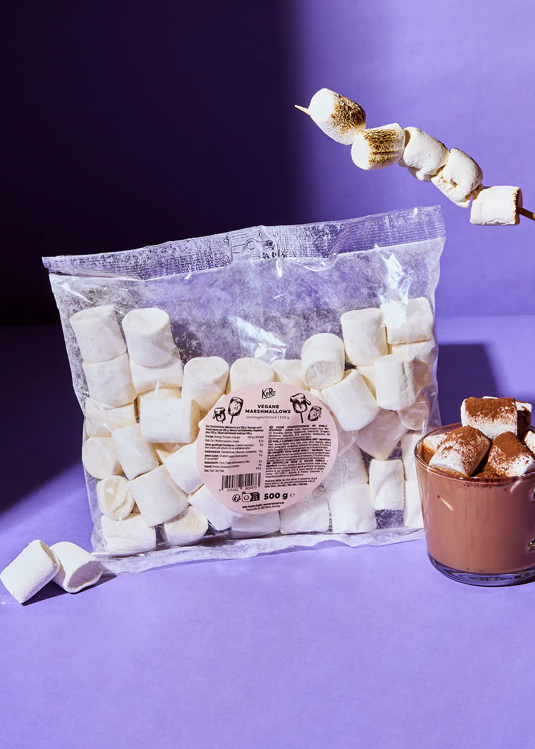 a bag of marshmallows is next to a cup of hot chocolate