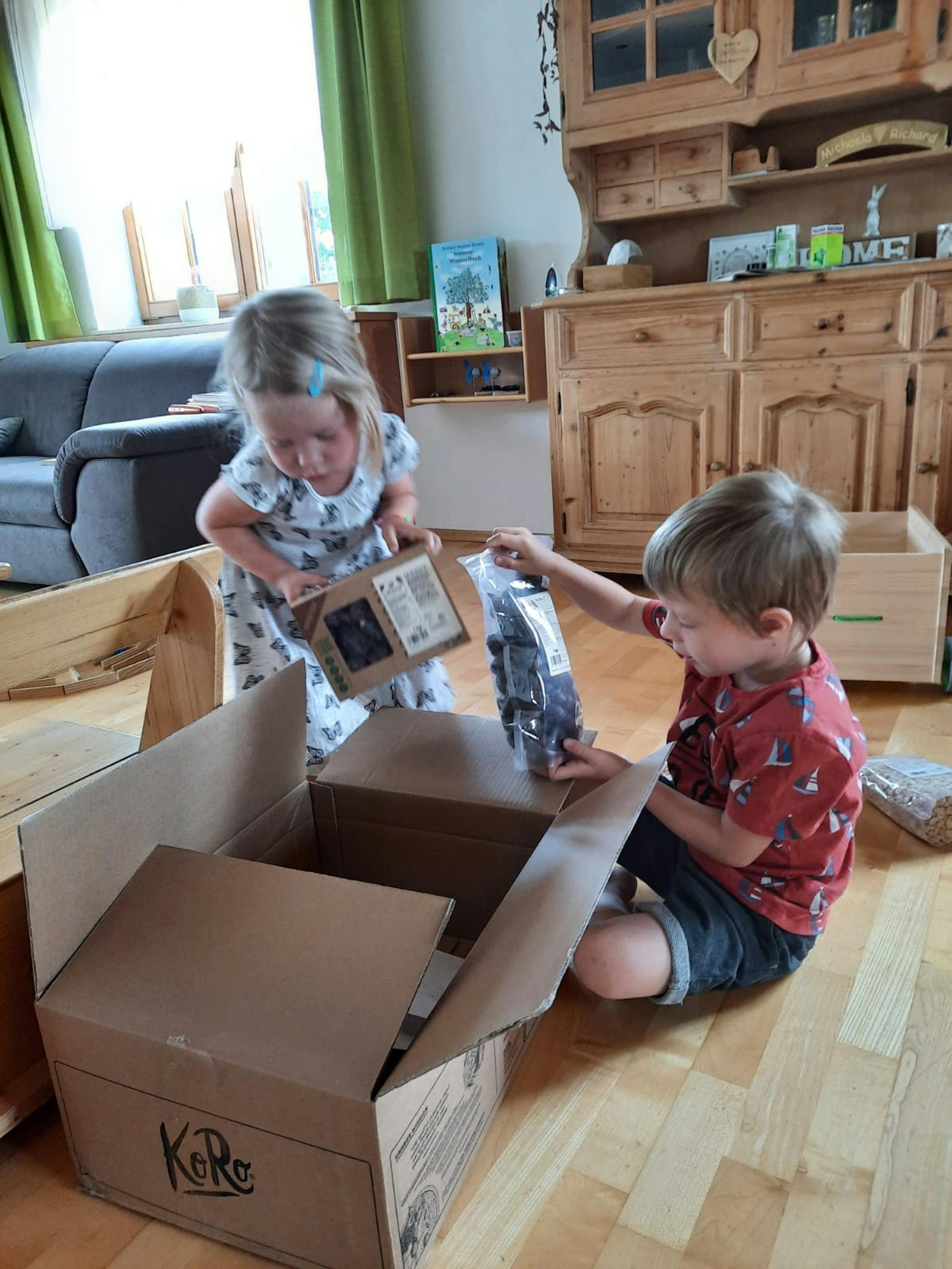 un ragazzo e una ragazza giocano con una scatola di cartone che dice kore