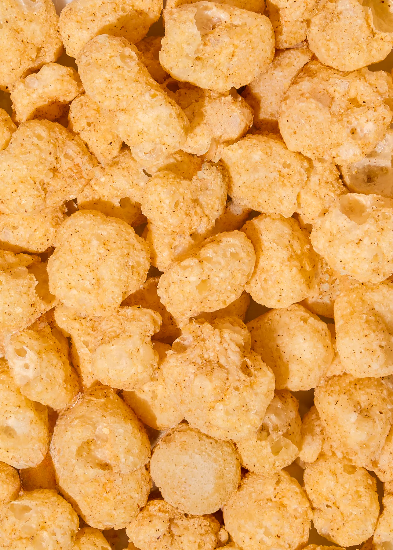 a close-up view of a pile of crunchy, golden-brown puffed corn snacks.