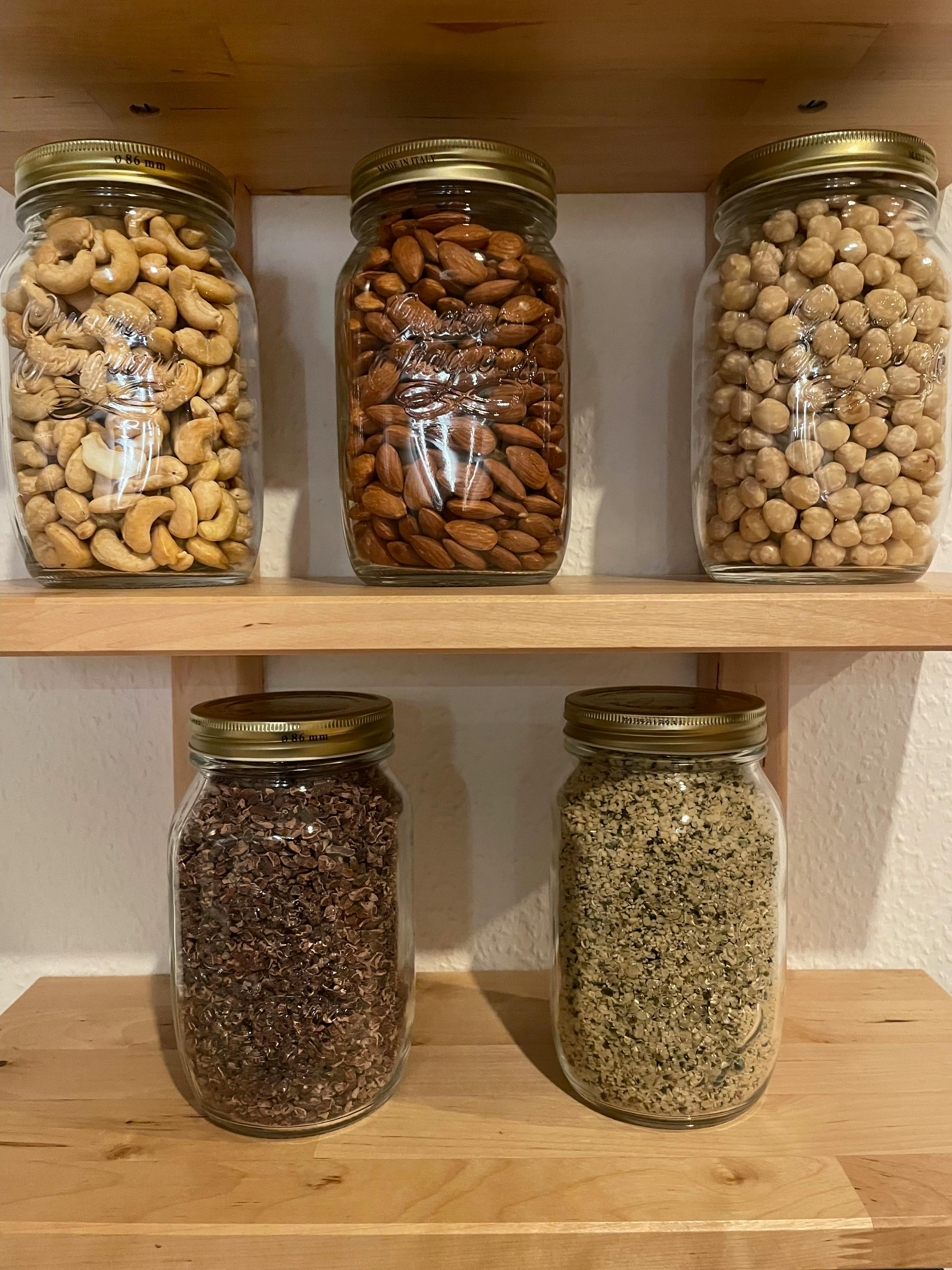 un scaffale di legno pieno di barattoli di vari tipi di frutta secca