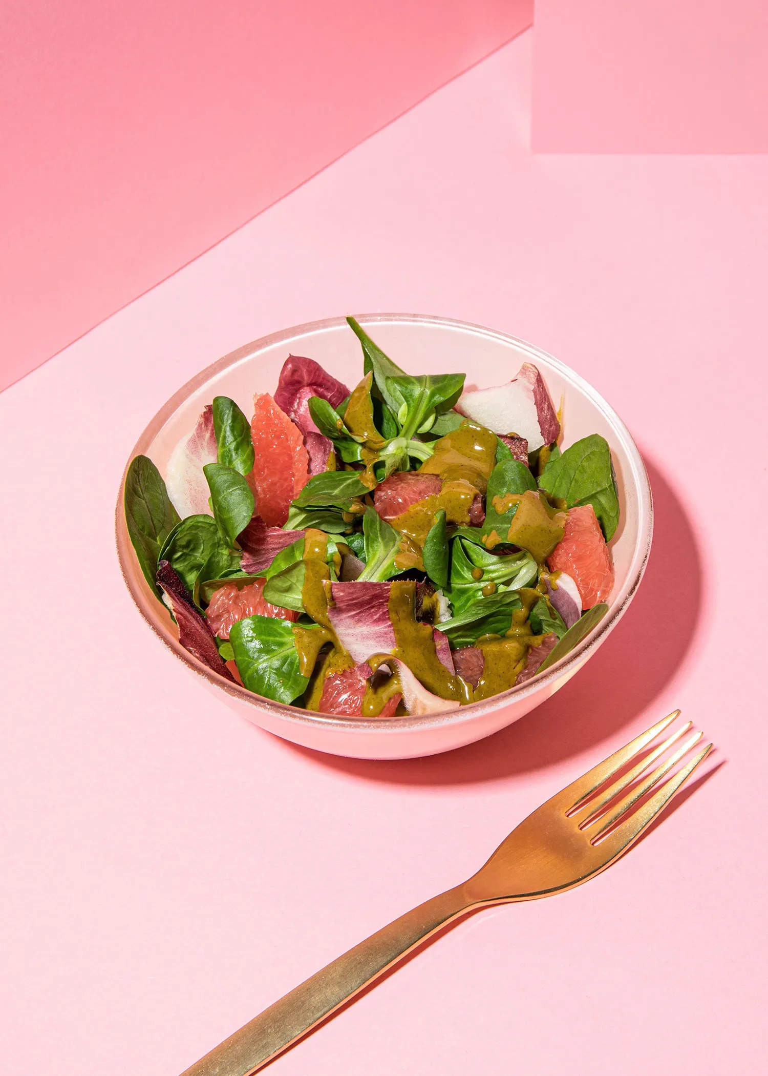 a salad in a bowl next to a gold fork