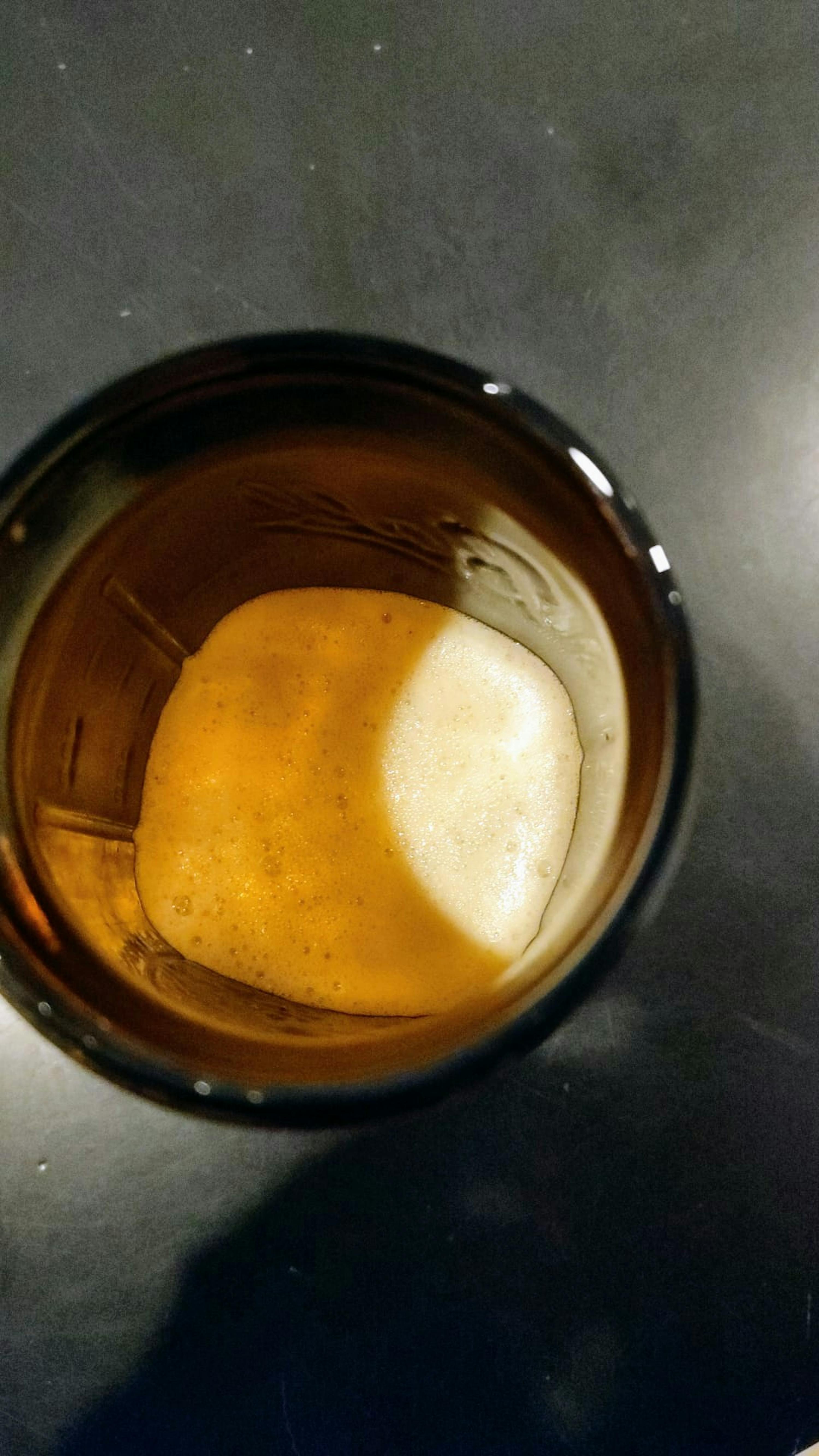 eine Nahaufnahme eines braunen Glases mit Schaum in der Mitte