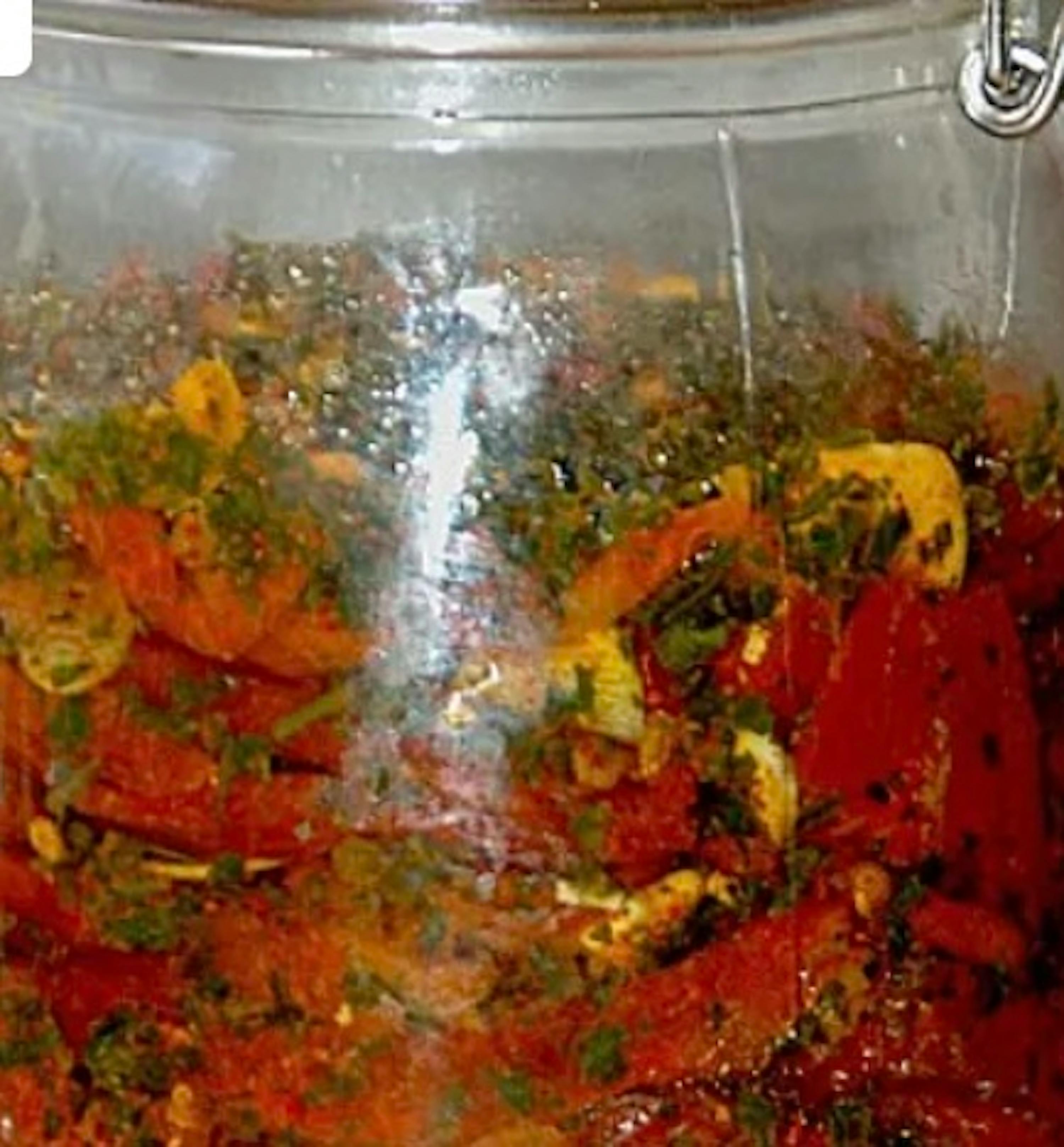 a close up of a jar filled with tomato sauce and vegetables .