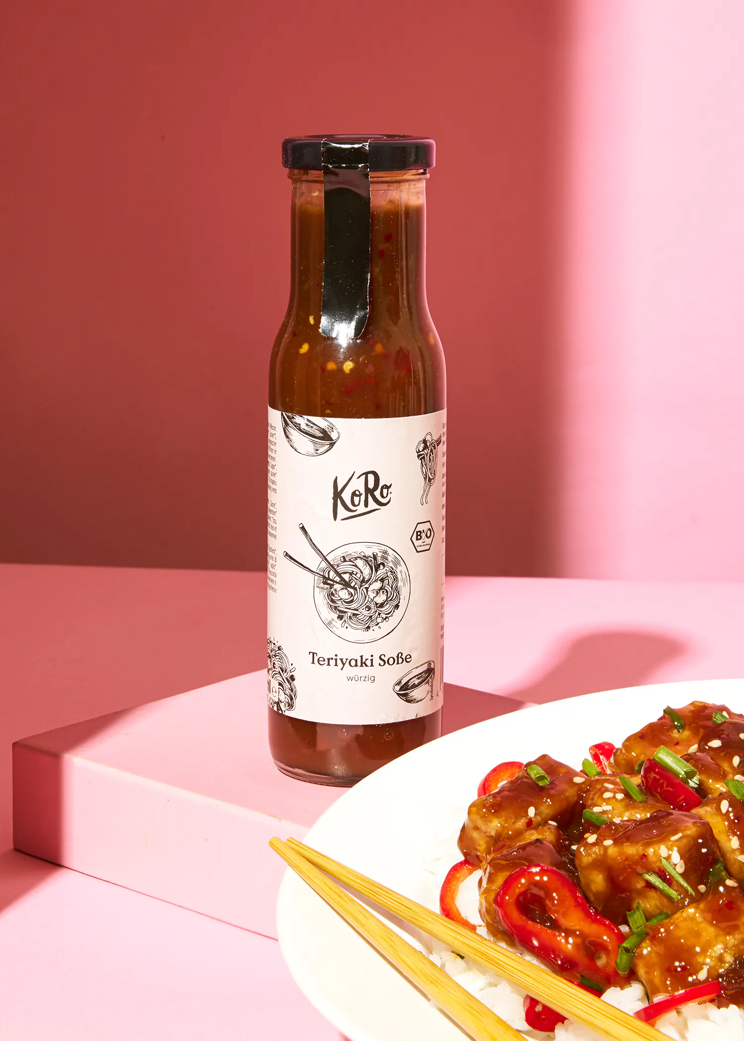 une bouteille de sauce teriyaki posée à côté d' une assiette de nourriture