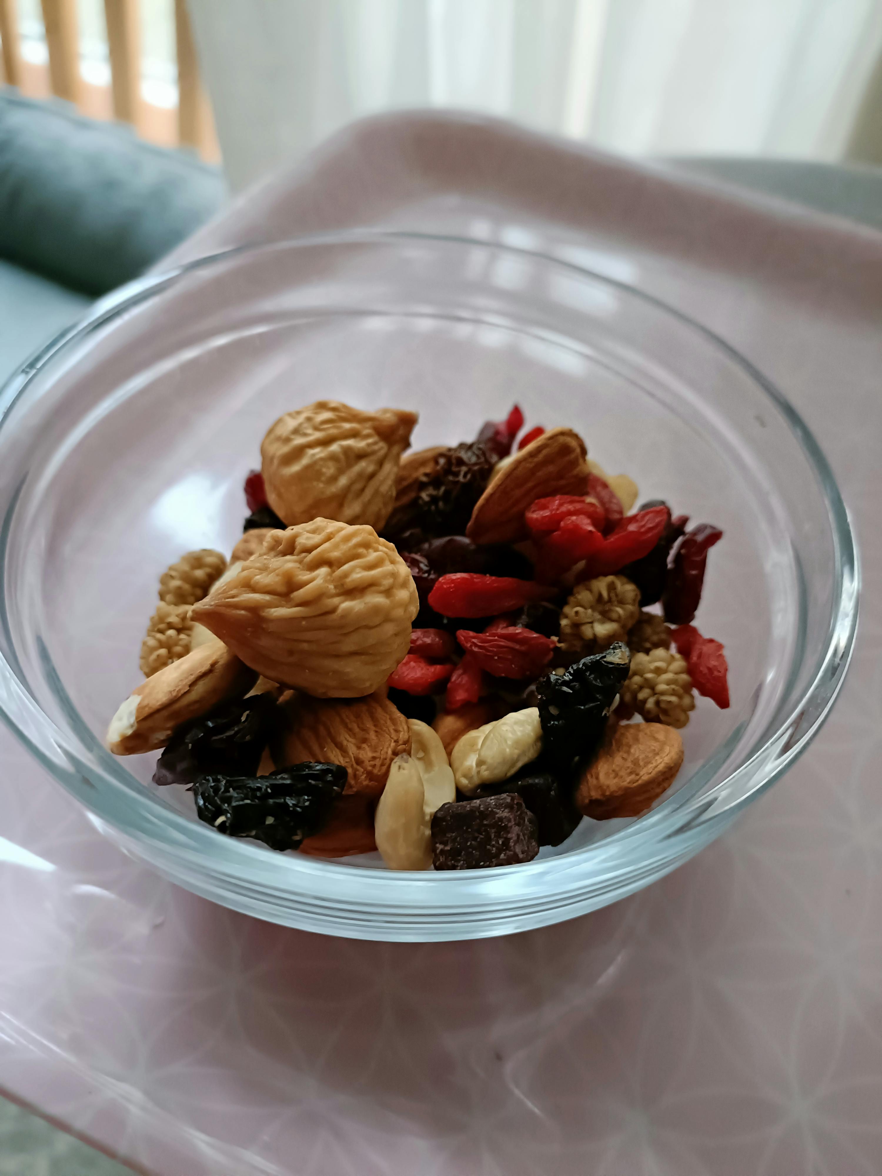 eine Glasschale mit Nüssen und Trockenfrüchten auf einem Tisch