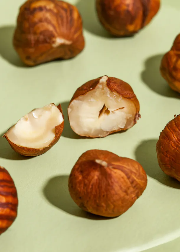 a hazelnut is cut in half on a green surface