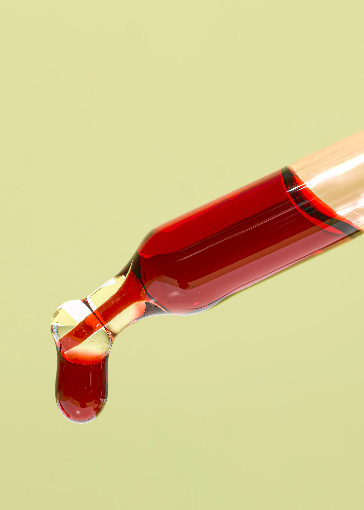 une pipette remplie d' un liquide rouge avec une goutte qui sort de la pipette