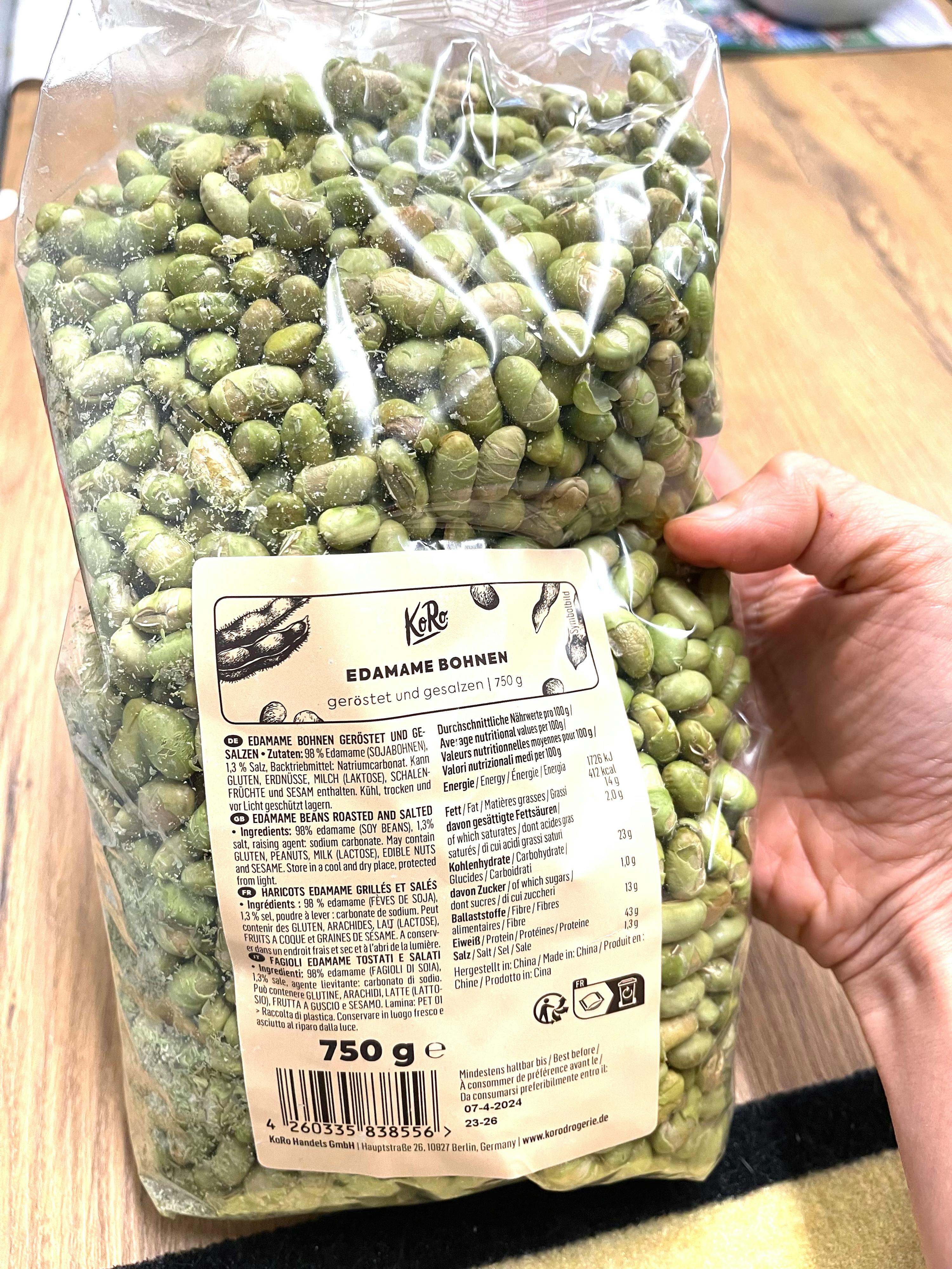 a person is holding a bag of edamame bohnen