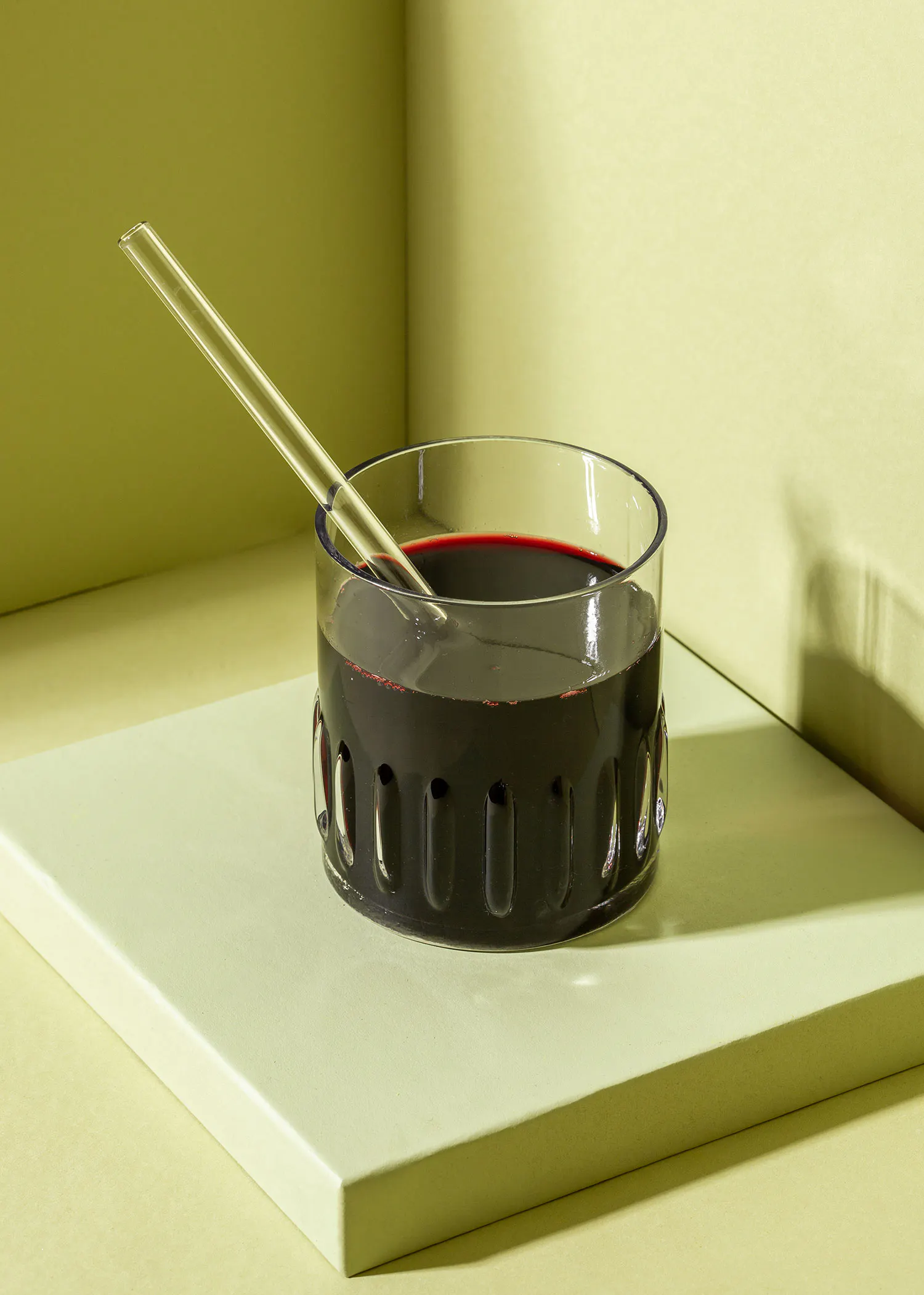 a glass with a straw in it filled with a dark liquid
