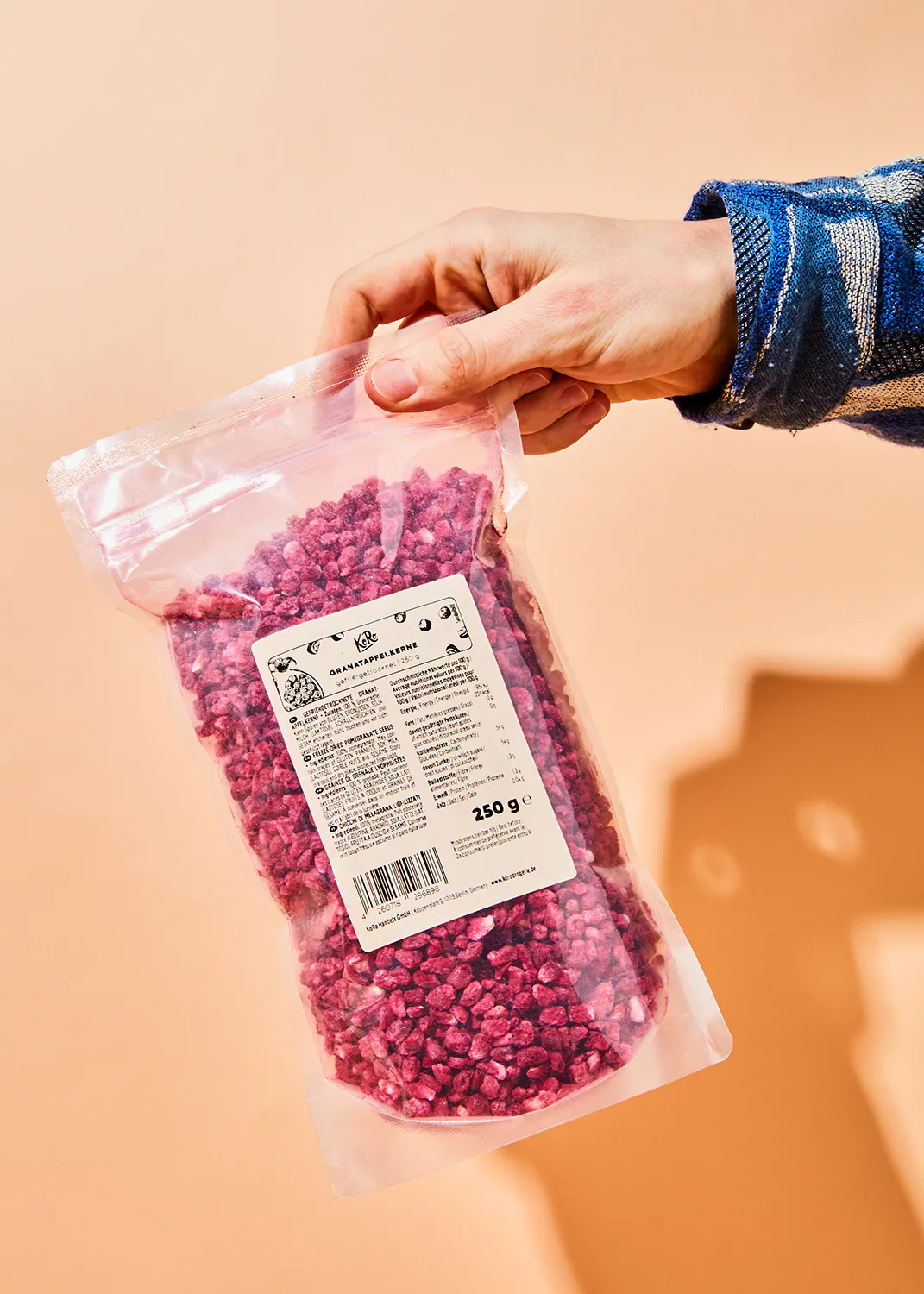 a person is holding a bag of dried raspberries