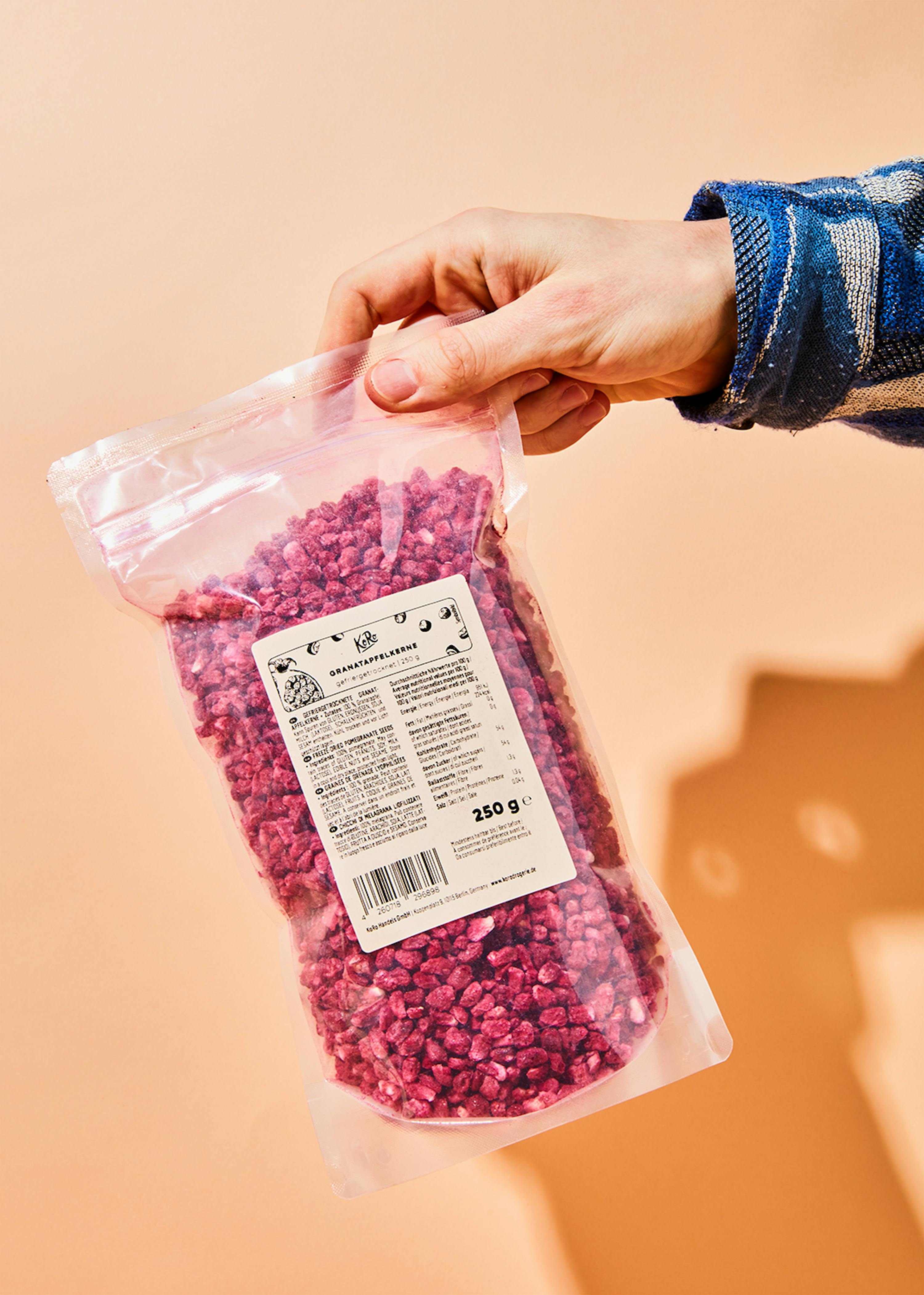 a person is holding a bag of dried raspberries