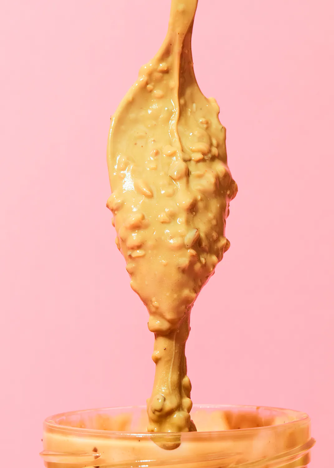 Erdnussbutter wird aus einem Löffel in ein Glas gegossen