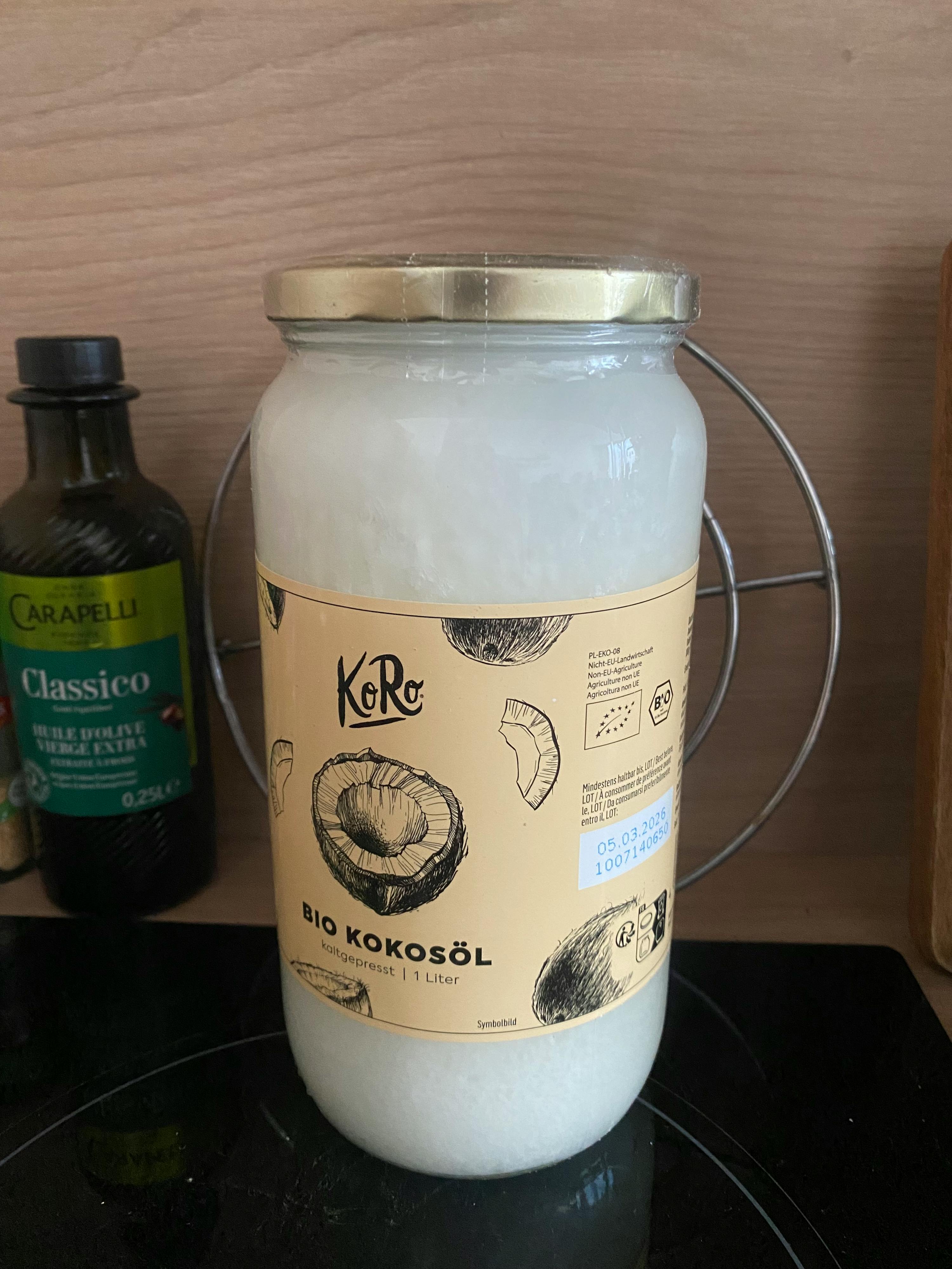 un barattolo di olio di cocco bio è seduto su un tavolo accanto a una bottiglia di classico