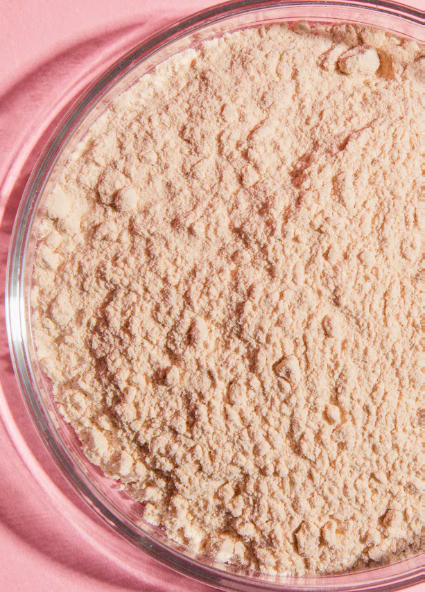 a glass bowl filled with powder on a pink surface