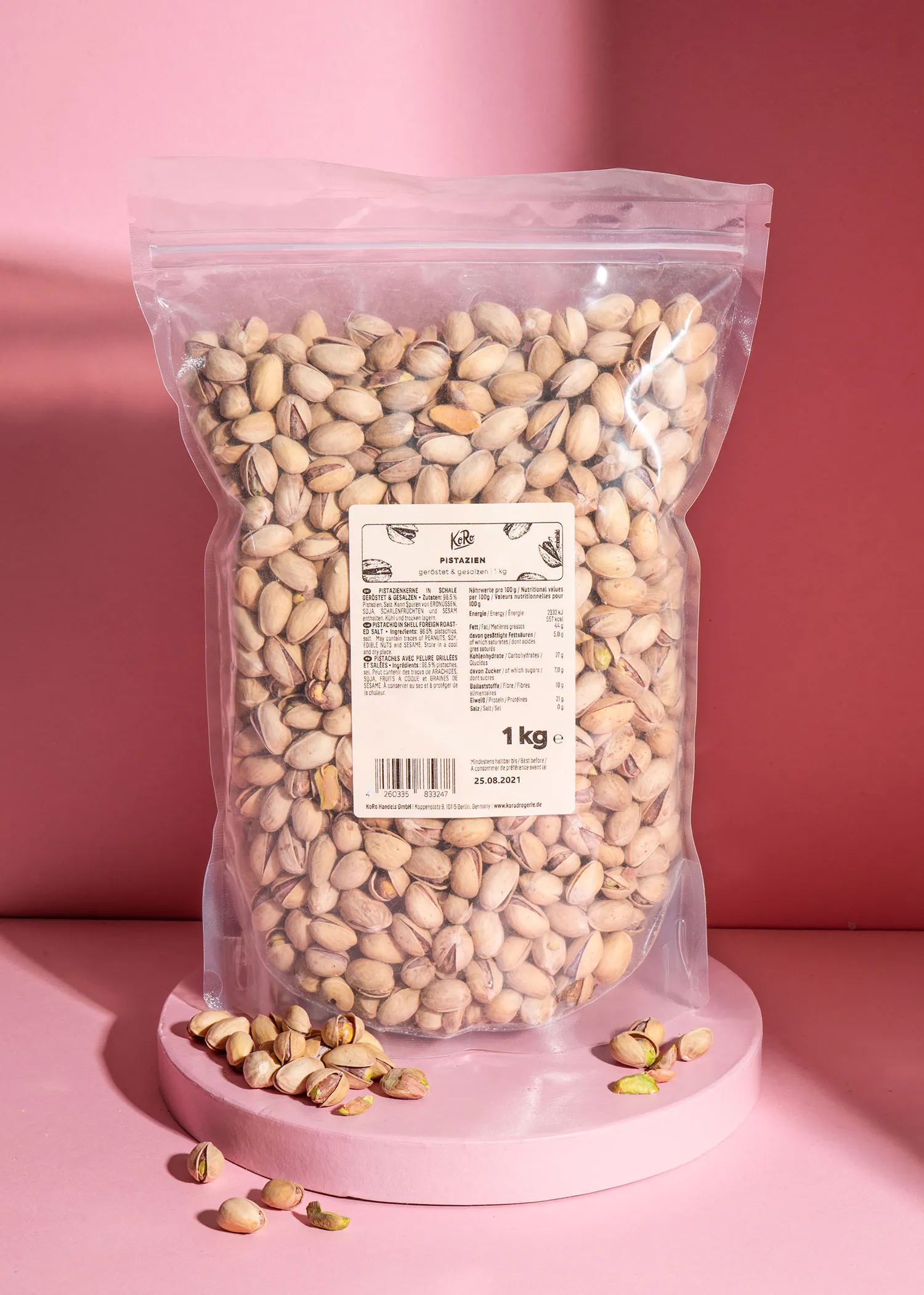ein Plastikbeutel mit pistazien steht auf einem rosa Tisch