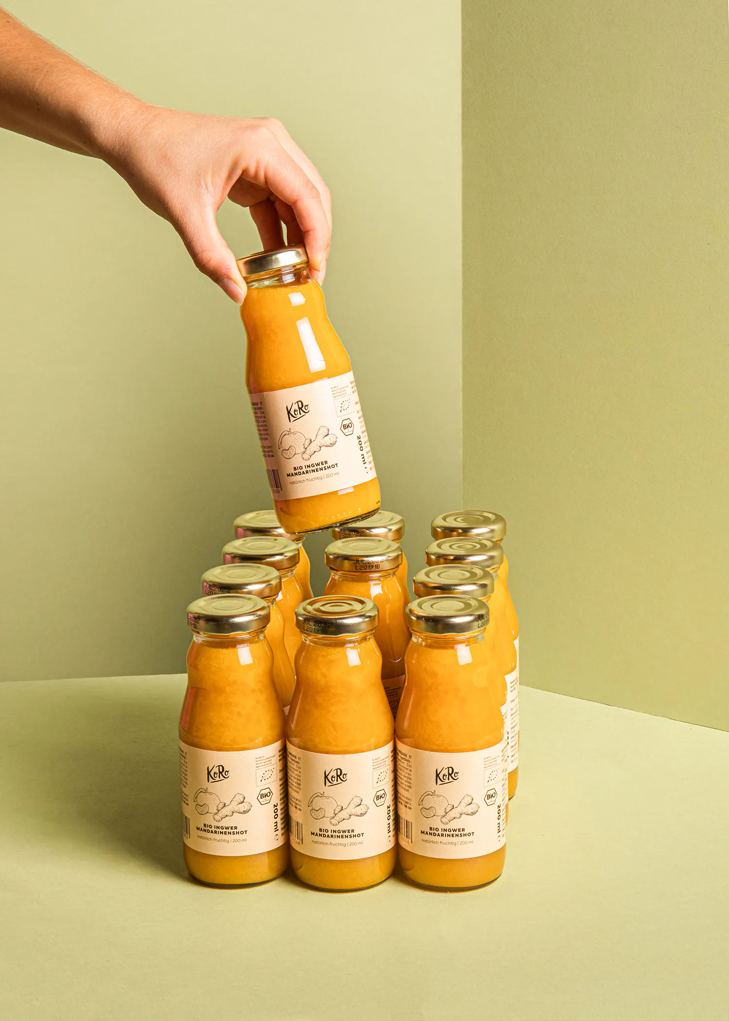 una persona sostiene una botella de jugo de kale encima de otras botellas de jugo de kale