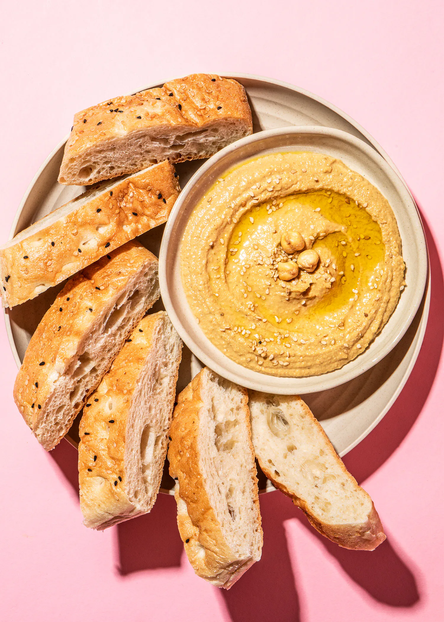 une assiette de pain et de hummus sur une table rose
