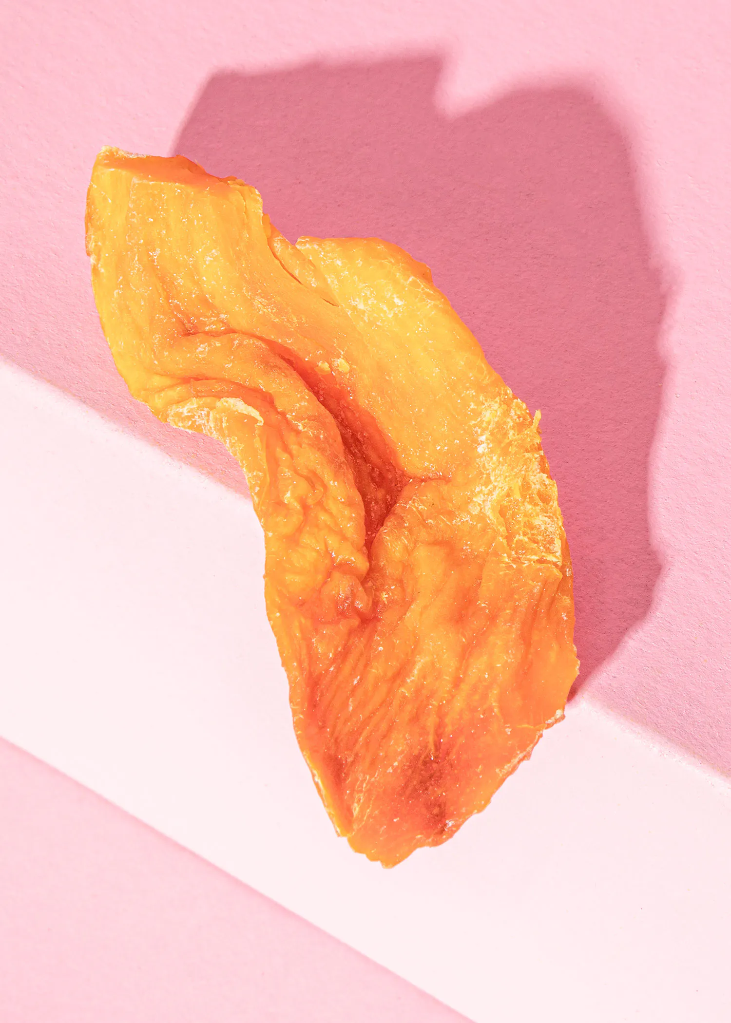 un morceau d' orange est posé sur une surface rose