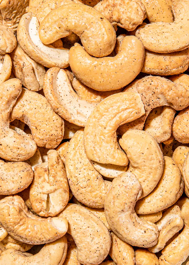 a pile of cashews with black pepper on them