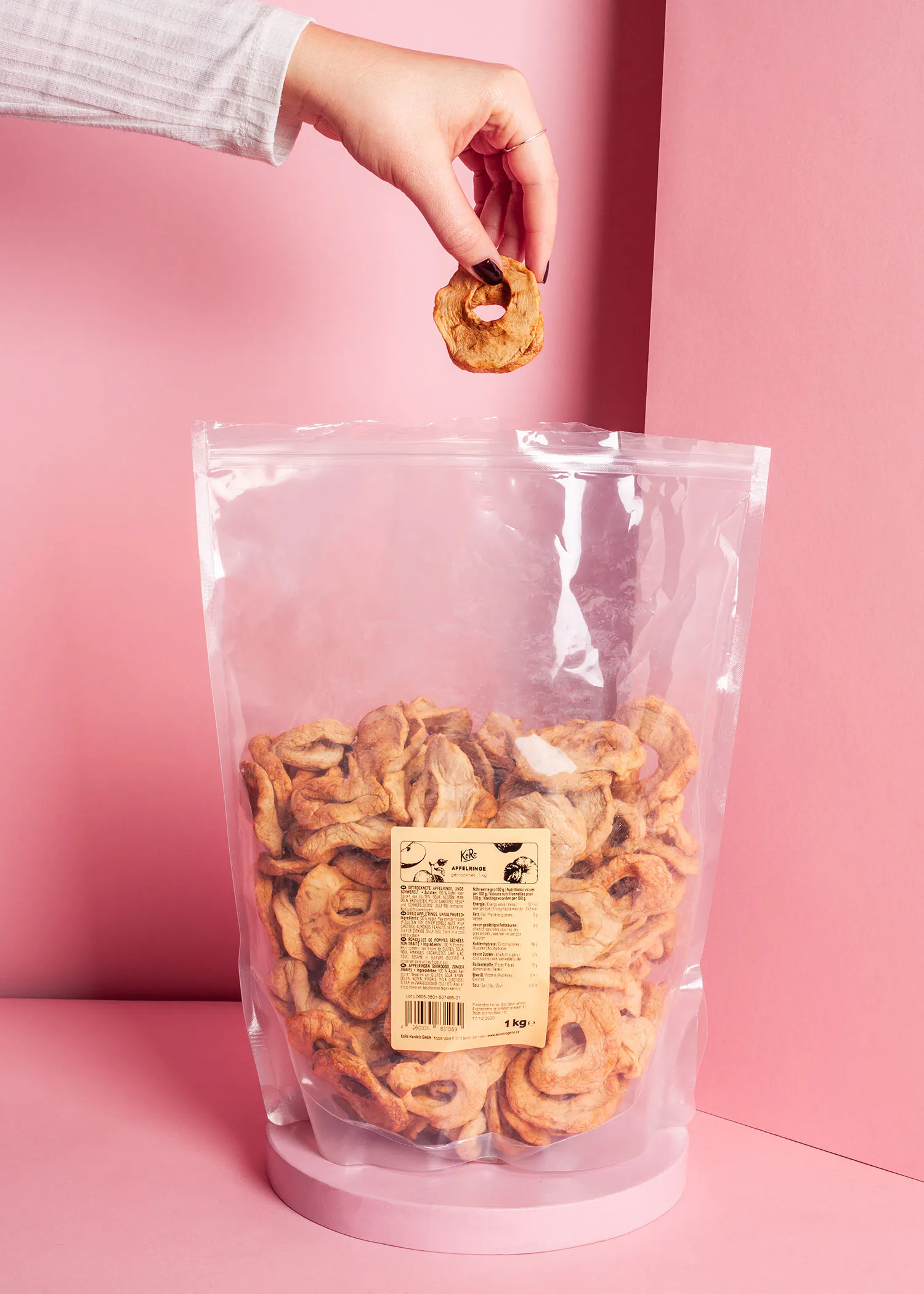 eine Person greift nach einem Apfelring aus einem Plastikbeutel