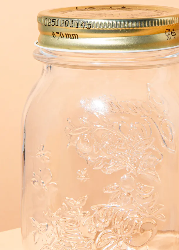 un gros plan d' un bocal en verre avec un couvercle doré