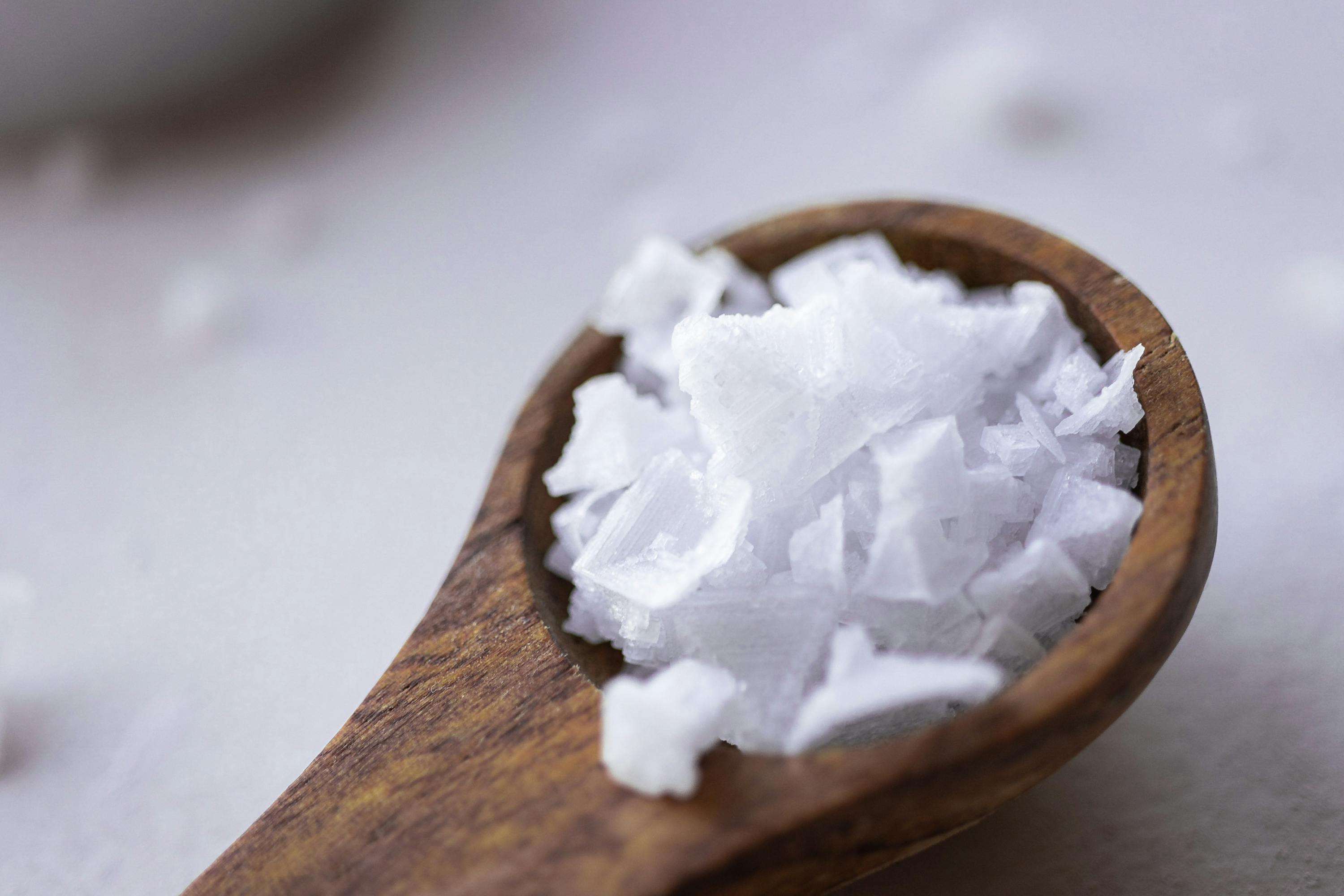 una cucchiaio di legno piena di sale bianco