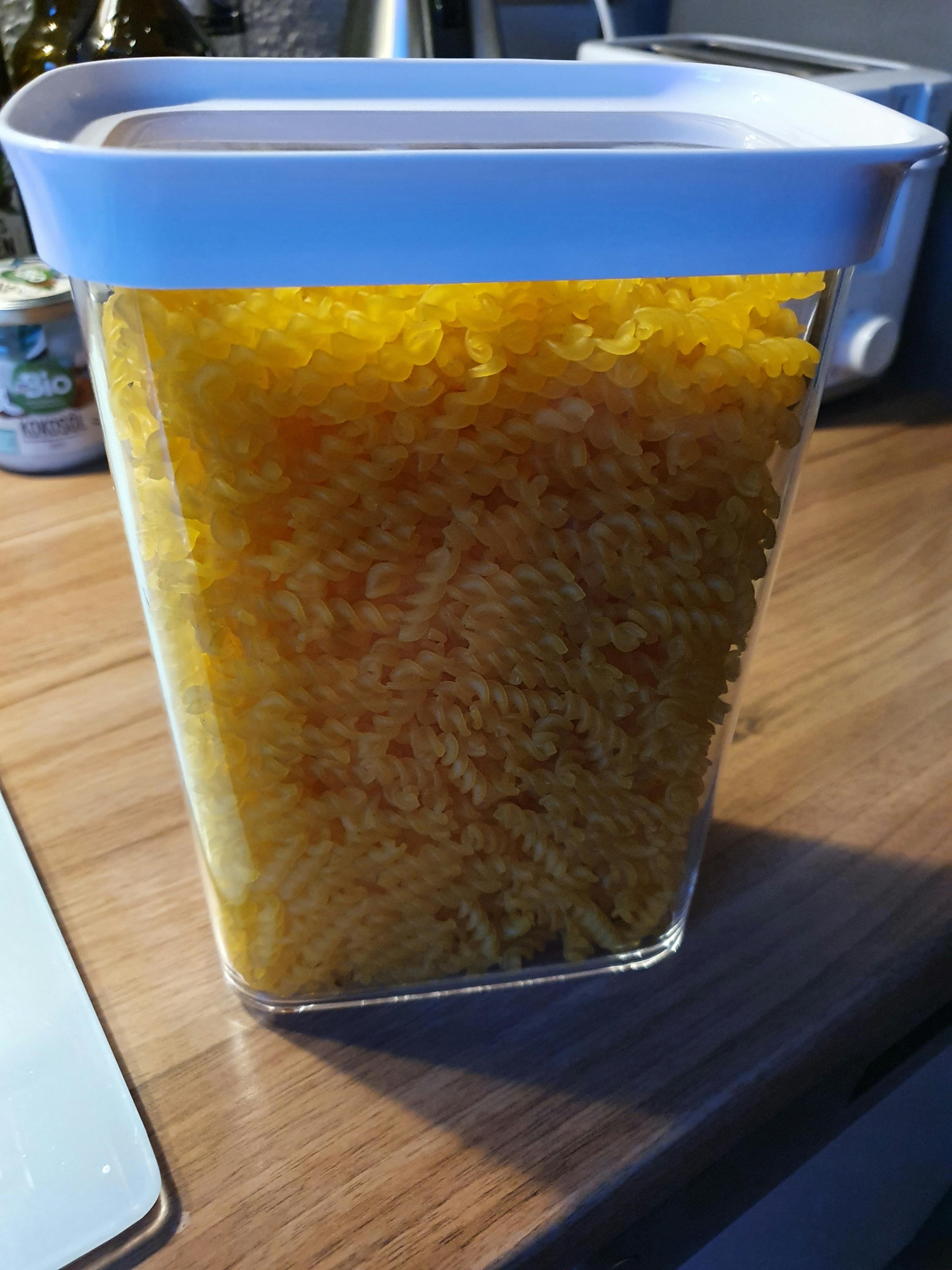 ein Glasgefäß voller Nudeln steht auf einem Holztisch