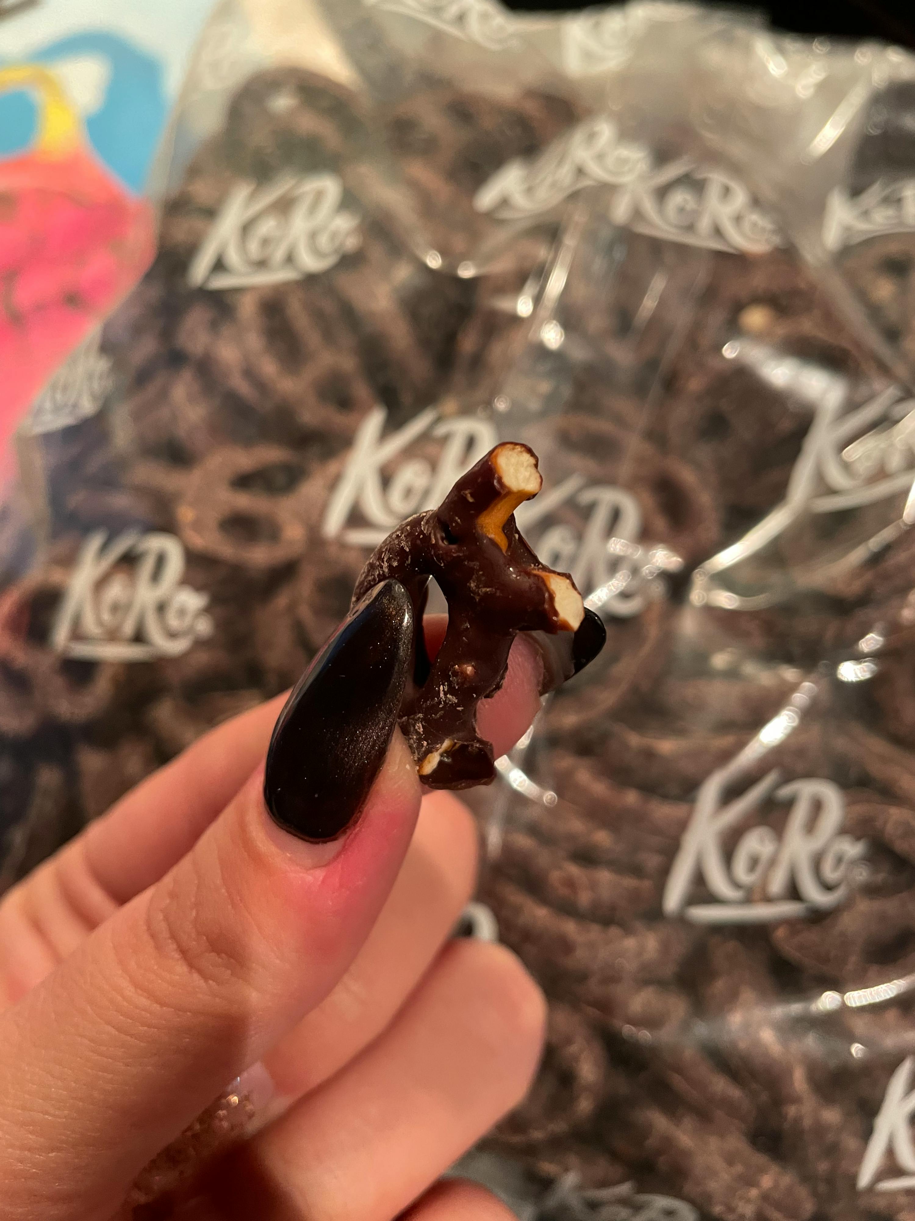 eine Person mit langen Nägeln hält einen Stück Schokolade in der Hand