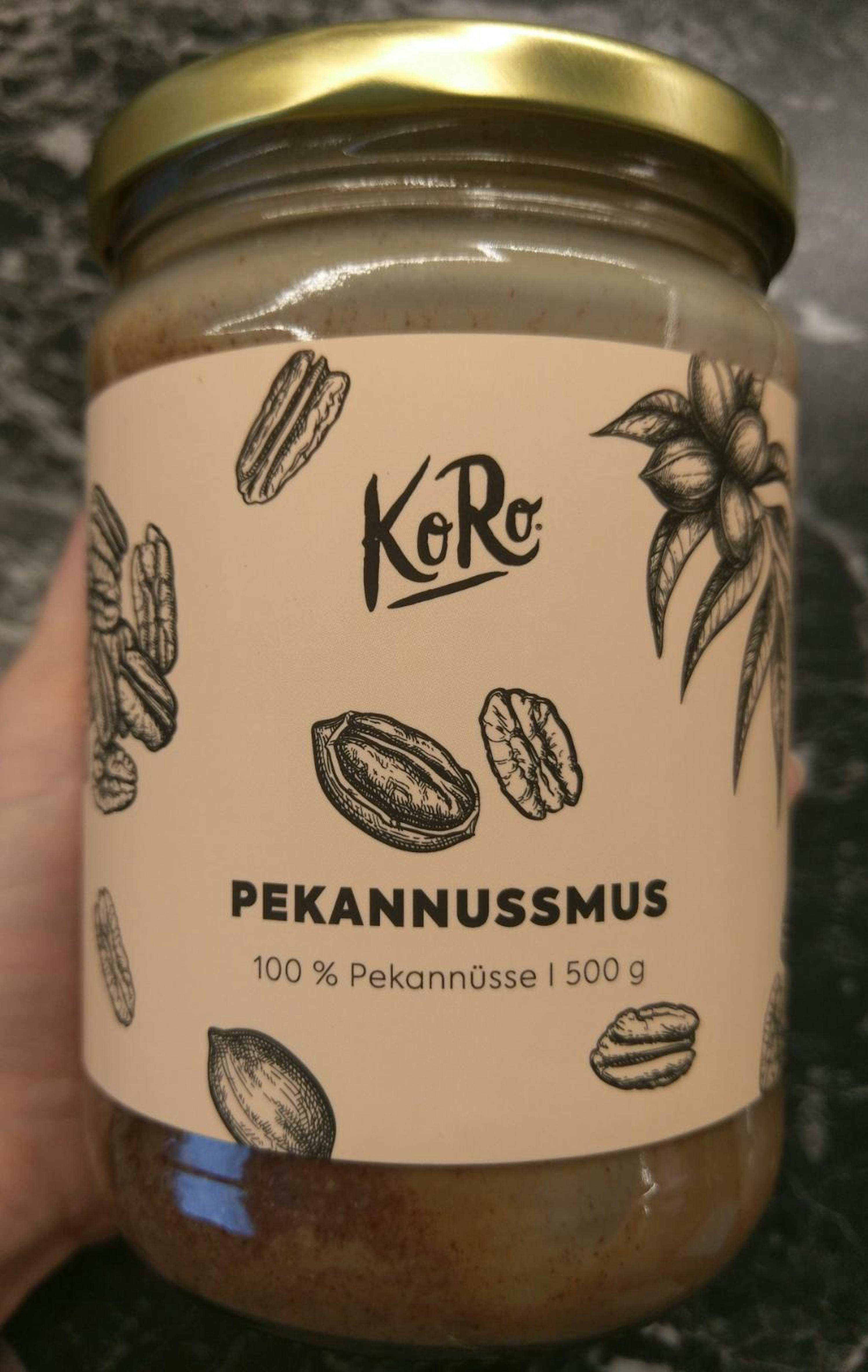 une personne tient un bocal de pecannusmus avec des noix de pécan sur l' étiquette