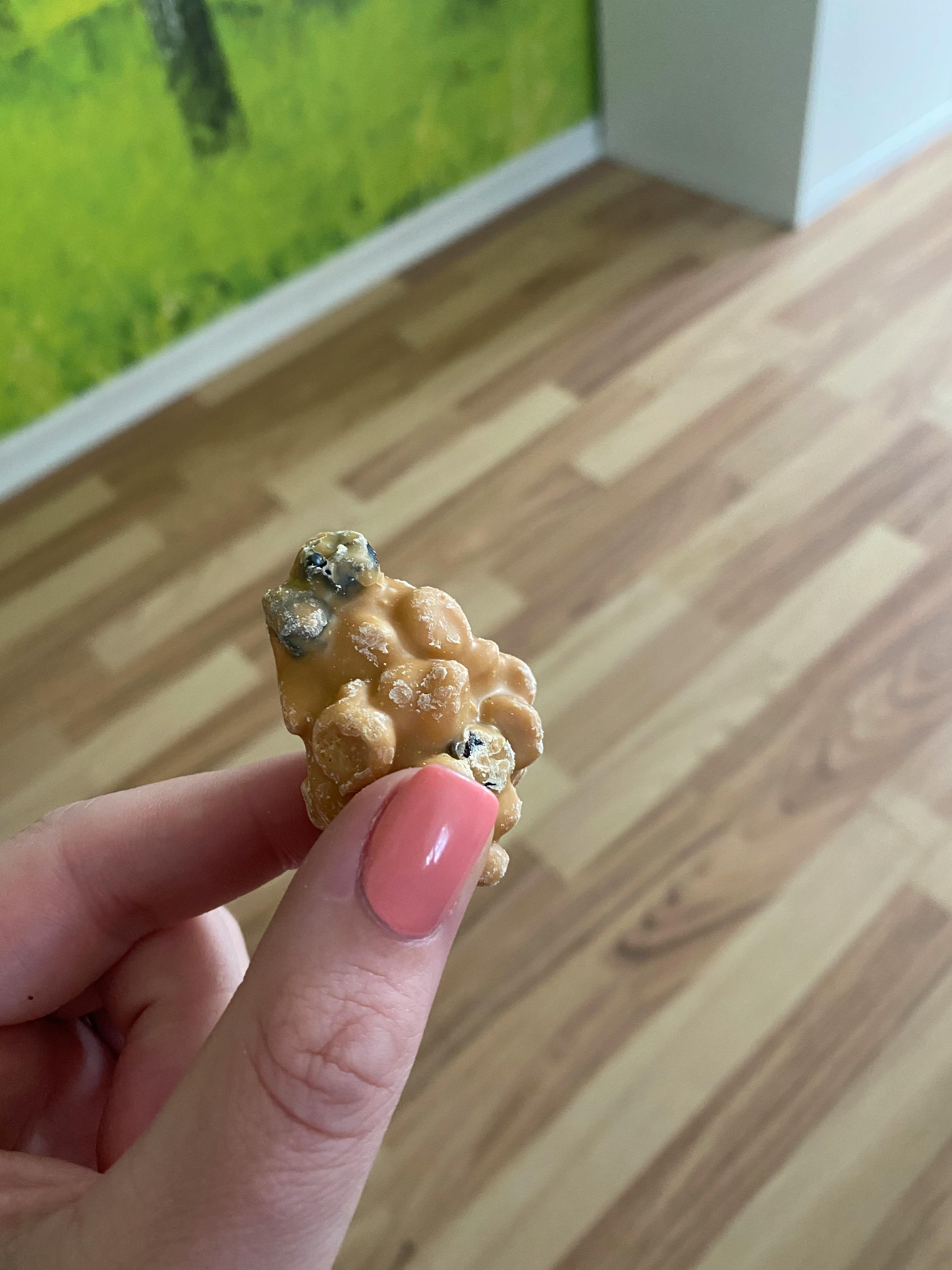 a person with pink nails holds a piece of popcorn in their hand