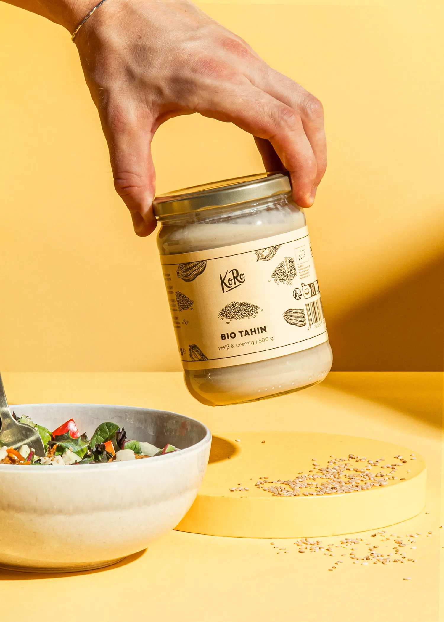 une personne tient un pot de tamin bio à côté d' un bol de nourriture