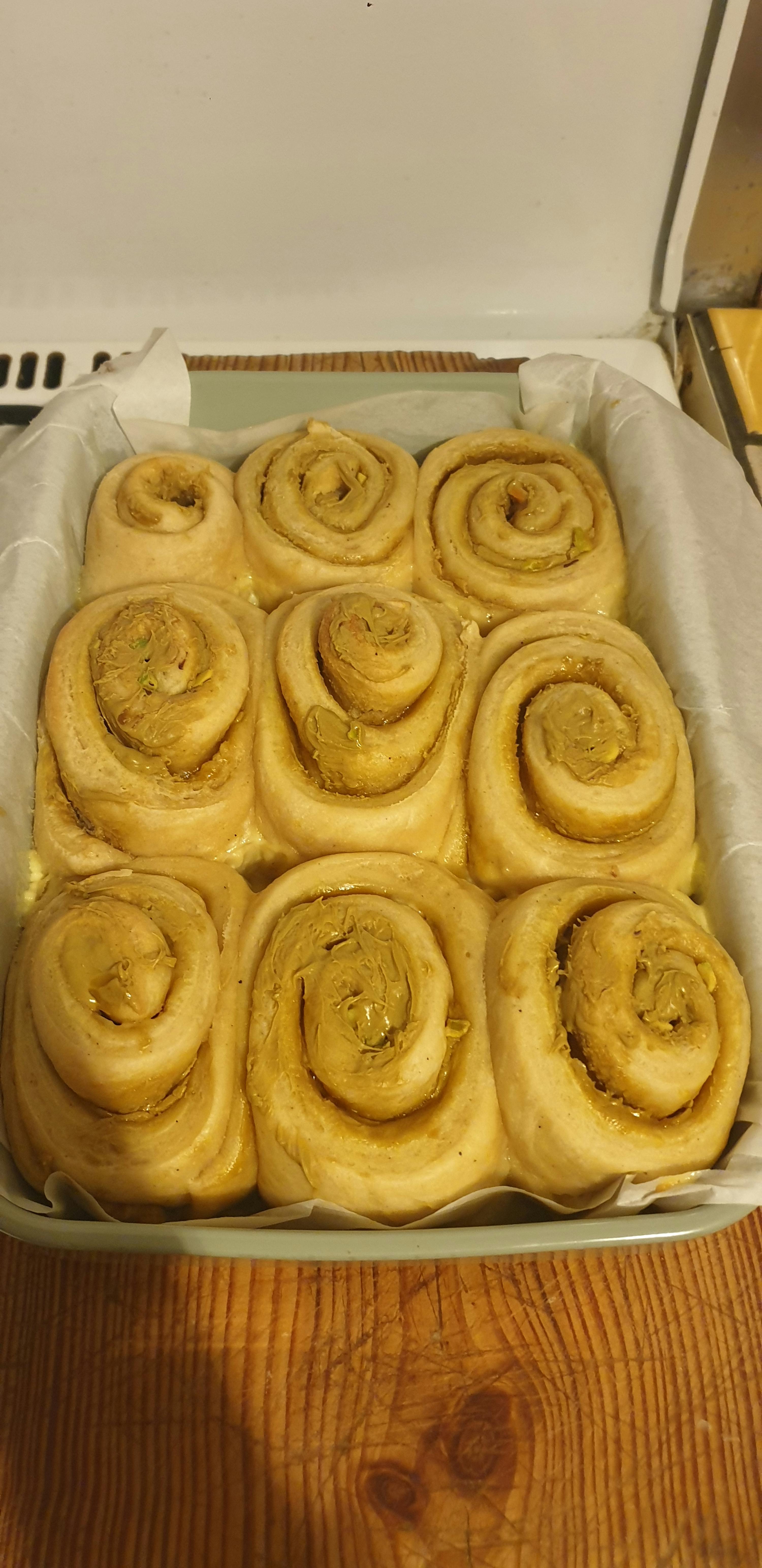 neuf brioches en spirale non cuites, garnies d'une pâte verdâtre, sont disposées dans un plat de cuisson rectangulaire, prêtes à être enfournées.