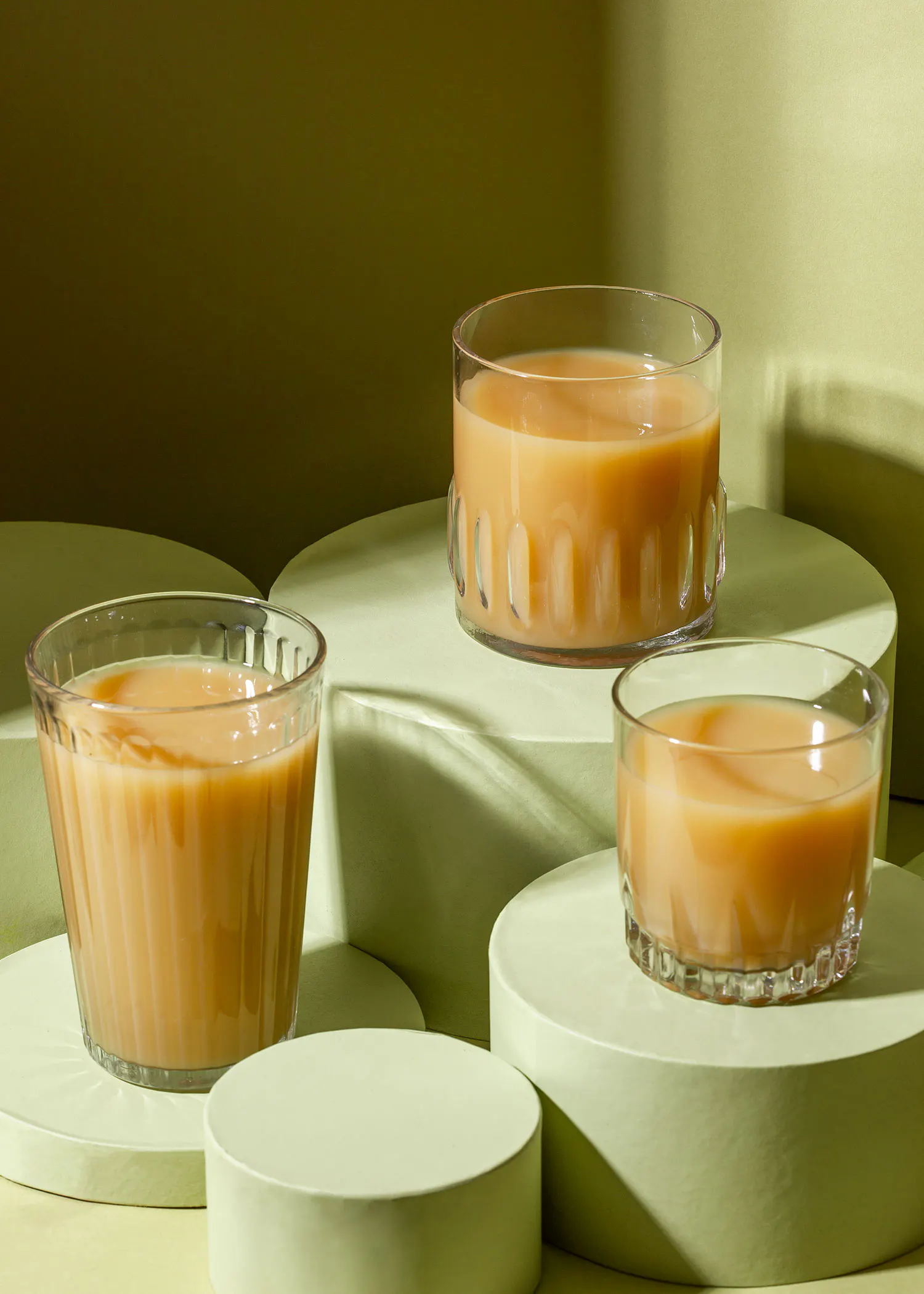 trois verres remplis de liquide sont posés sur des podiums verts