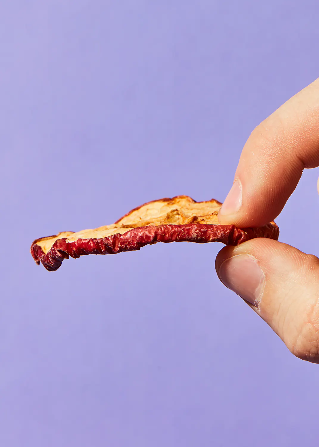 a person is holding a piece of food in their hand against a purple background