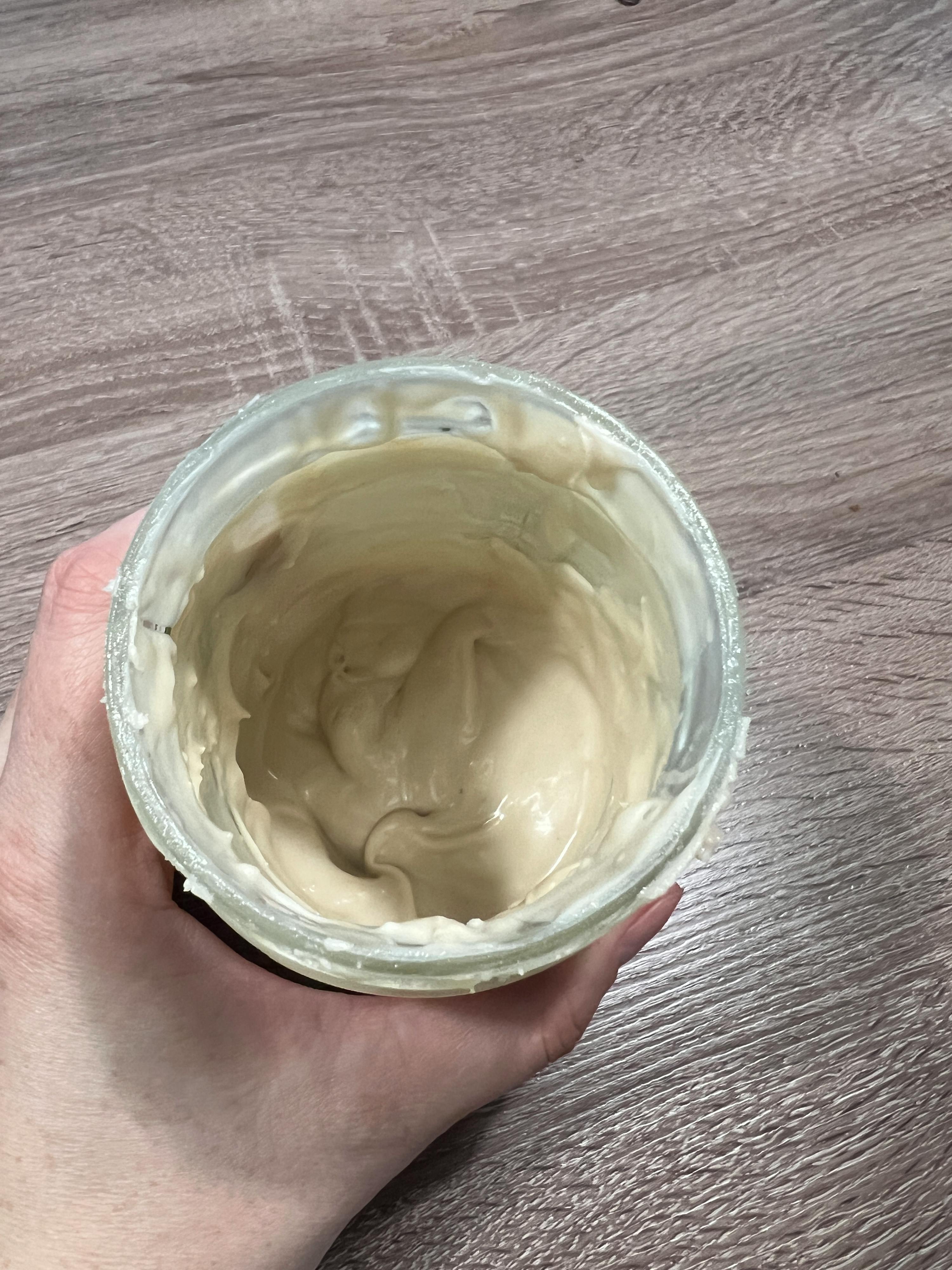 a hand is holding a jar of yogurt on a wooden table