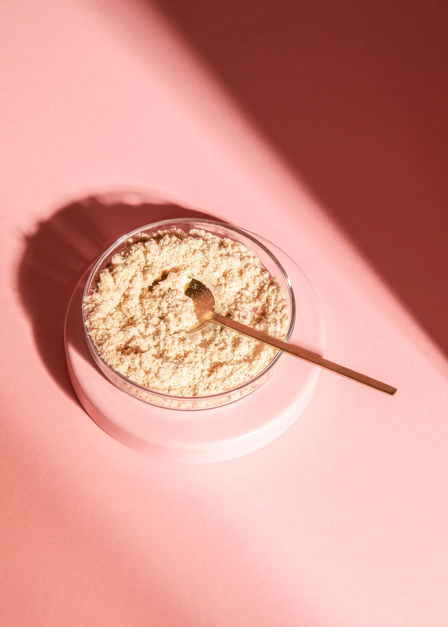 un bol en verre rempli de poudre et d' une cuillère