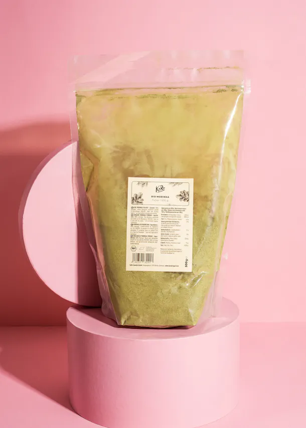 eine Plastiktüte mit einem Etikett auf der Rückseite steht auf einem rosa Sockel