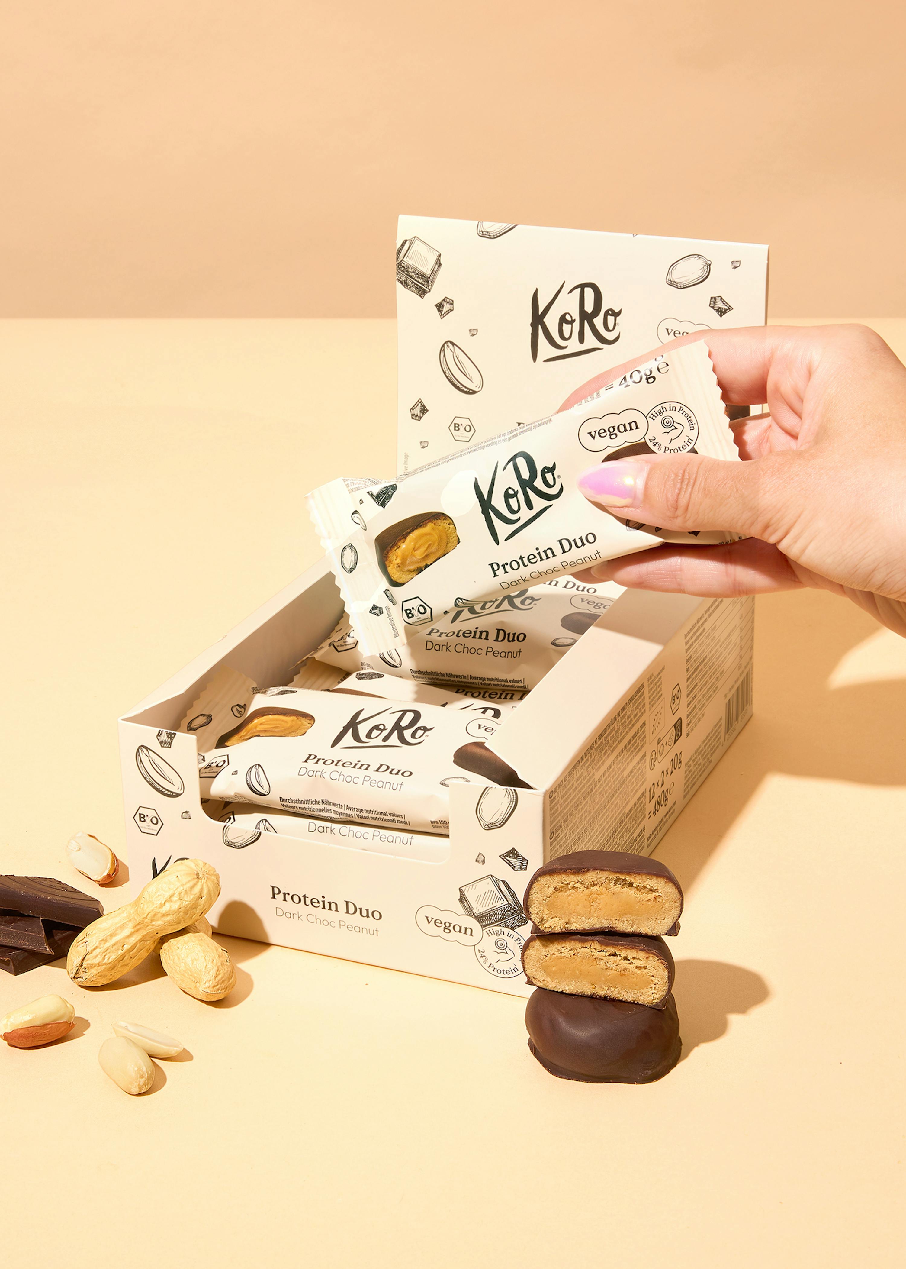 a person is holding a box of koko protein duo bars