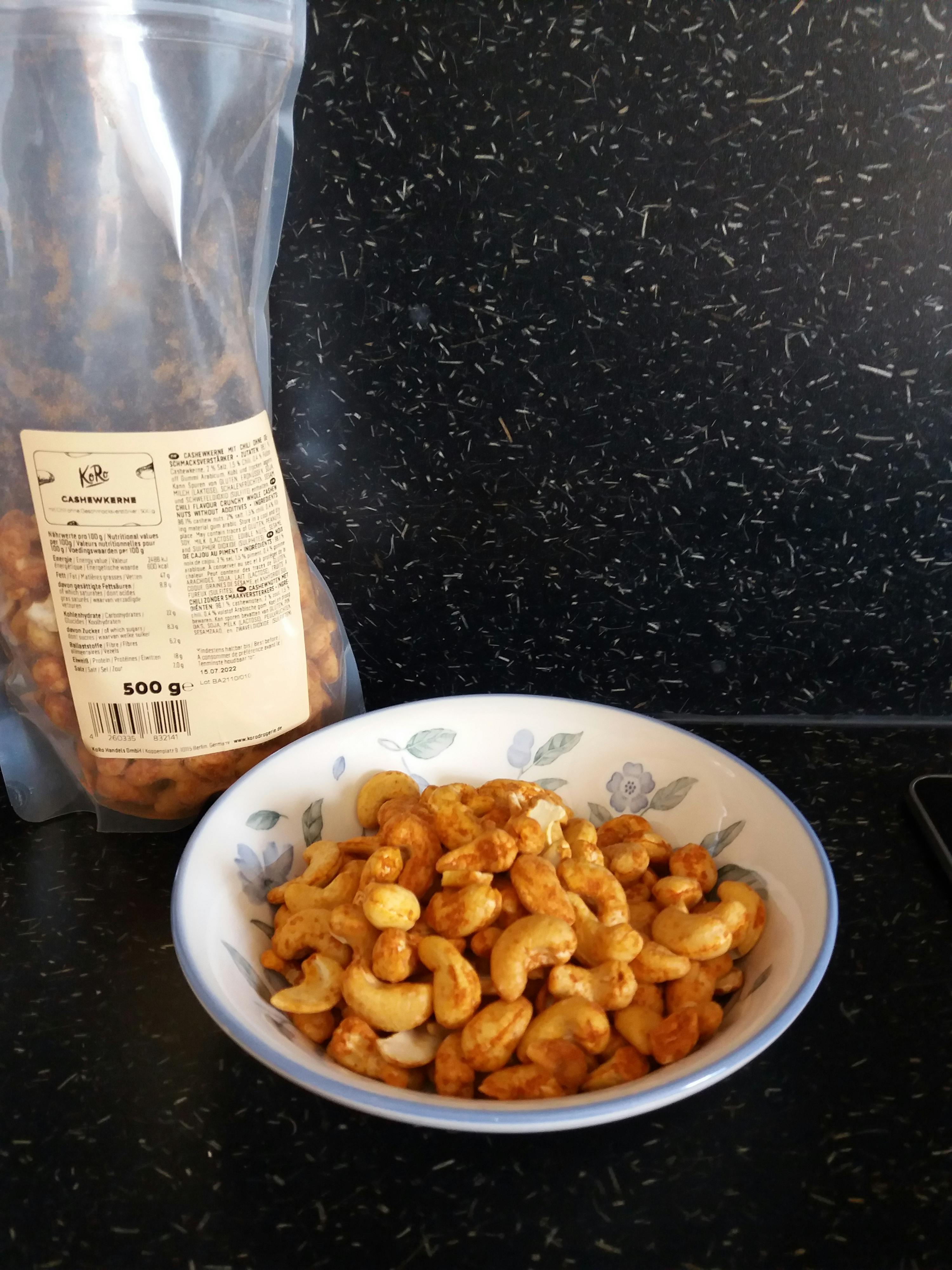 eine Tüte Cashewnüsse neben einer Schüssel mit Cashewnüssen
