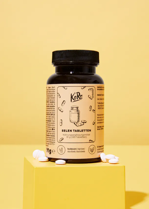 une bouteille de tablettes de sélénium de koro est posée sur une surface jaune