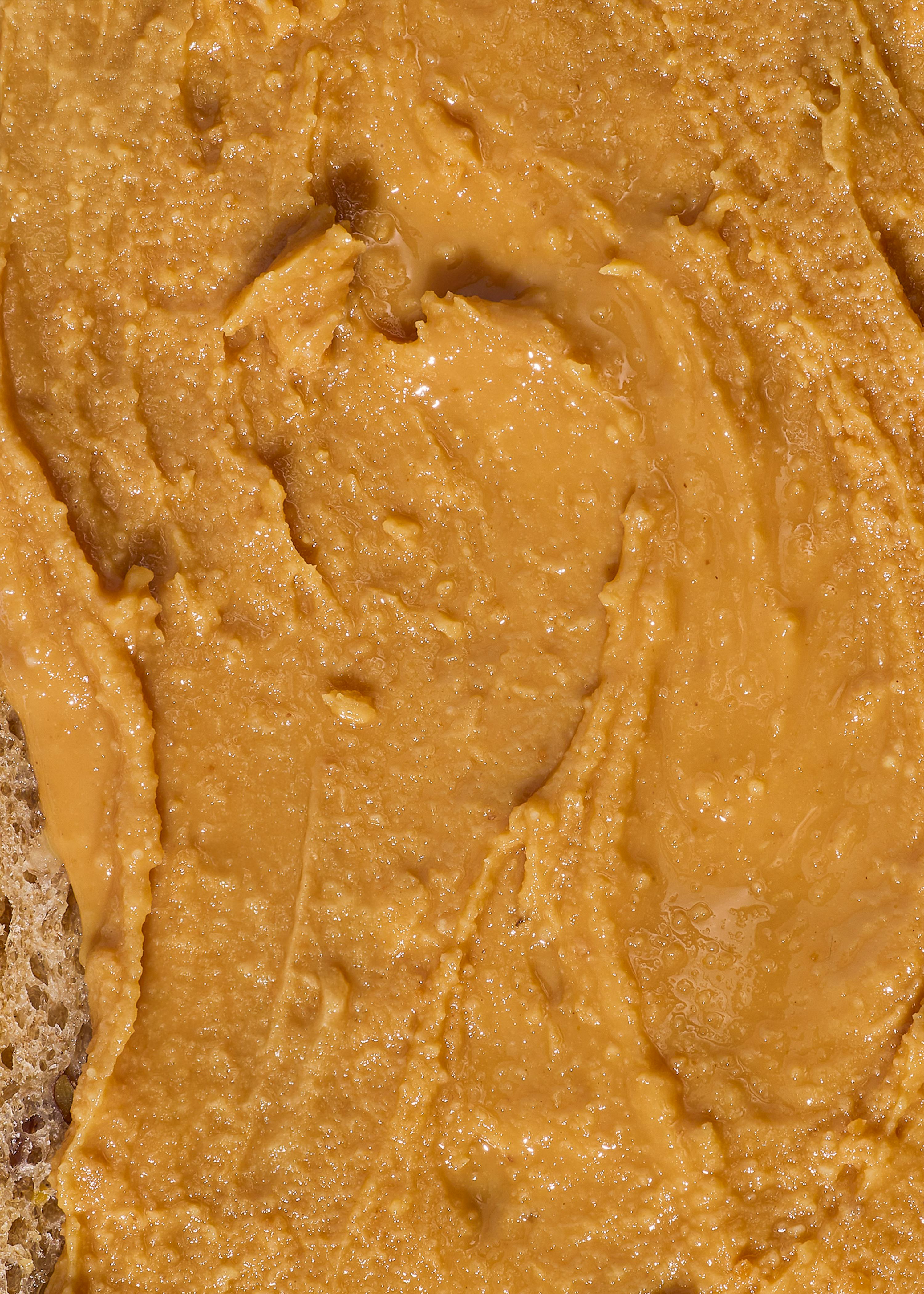 a close-up of textured peanut butter spread on a piece of bread.