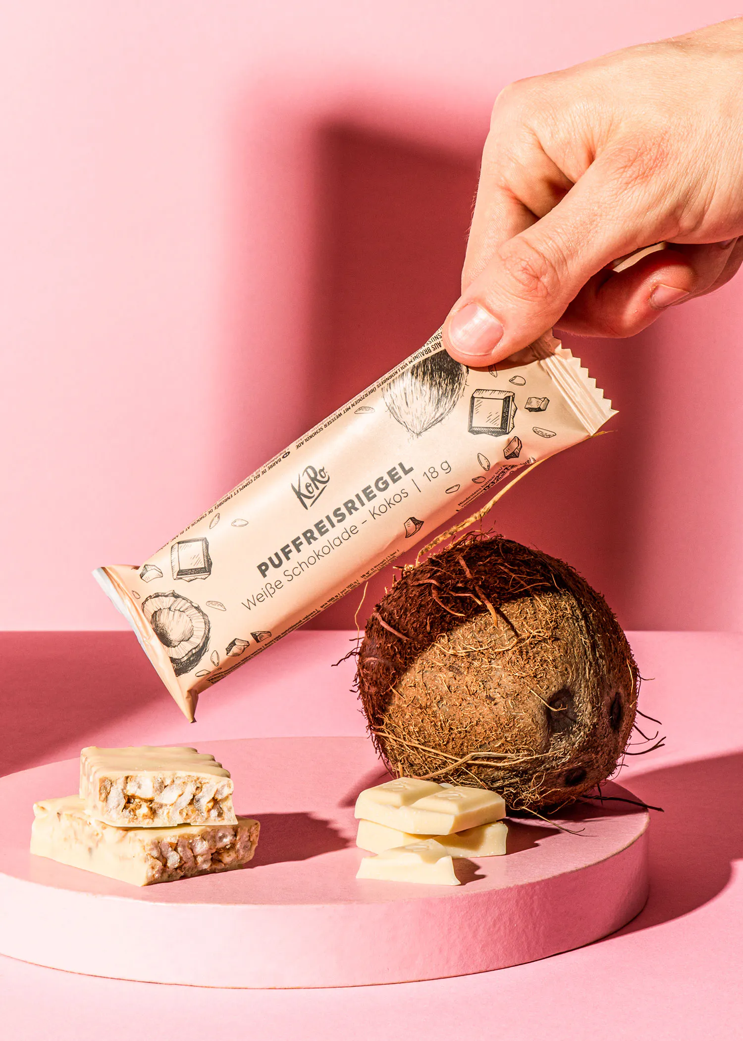 une personne tient une barre de chocolat avec une noix de coco à côté