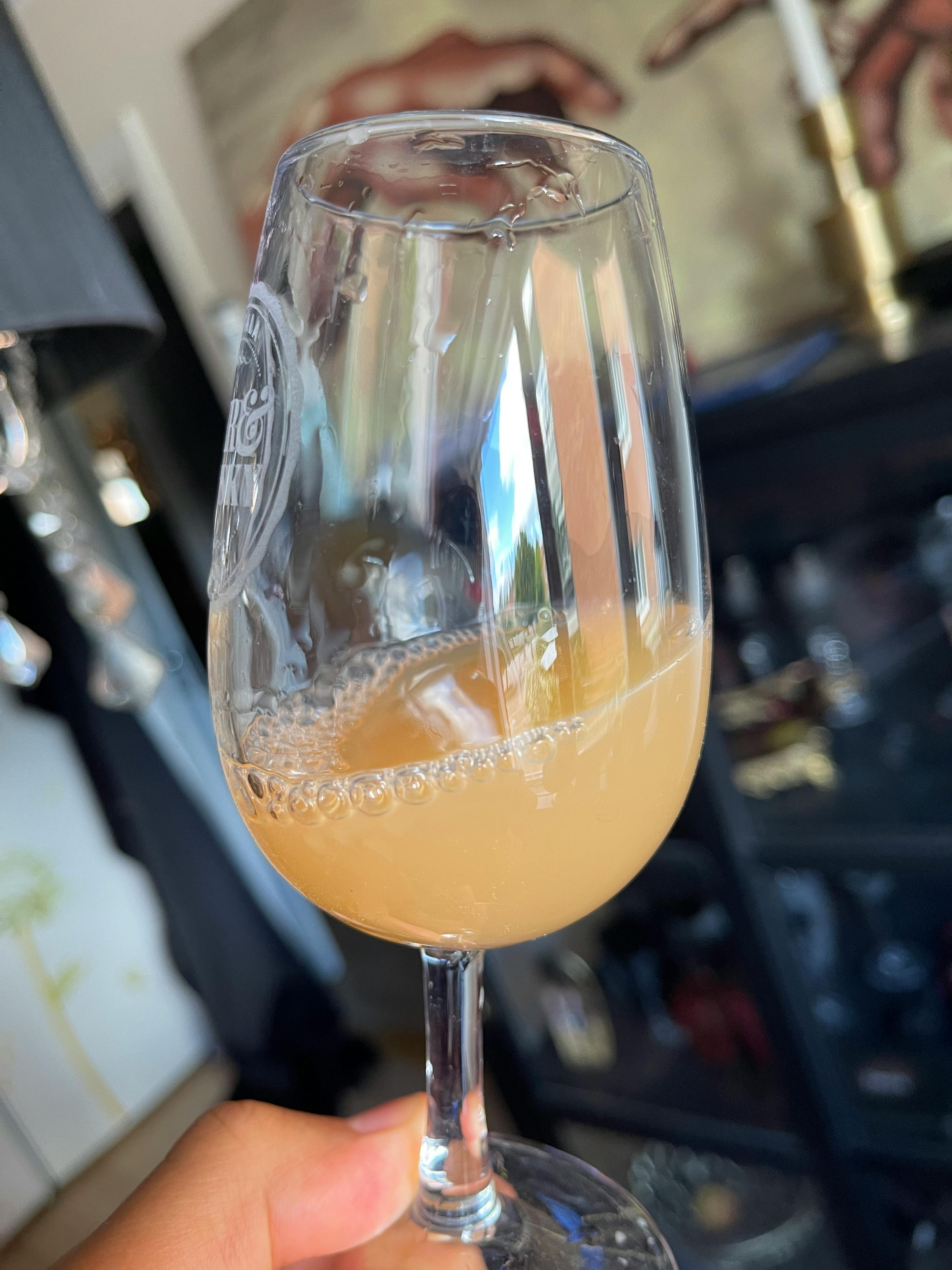 une personne tient un verre à vin rempli d' un liquide jaune