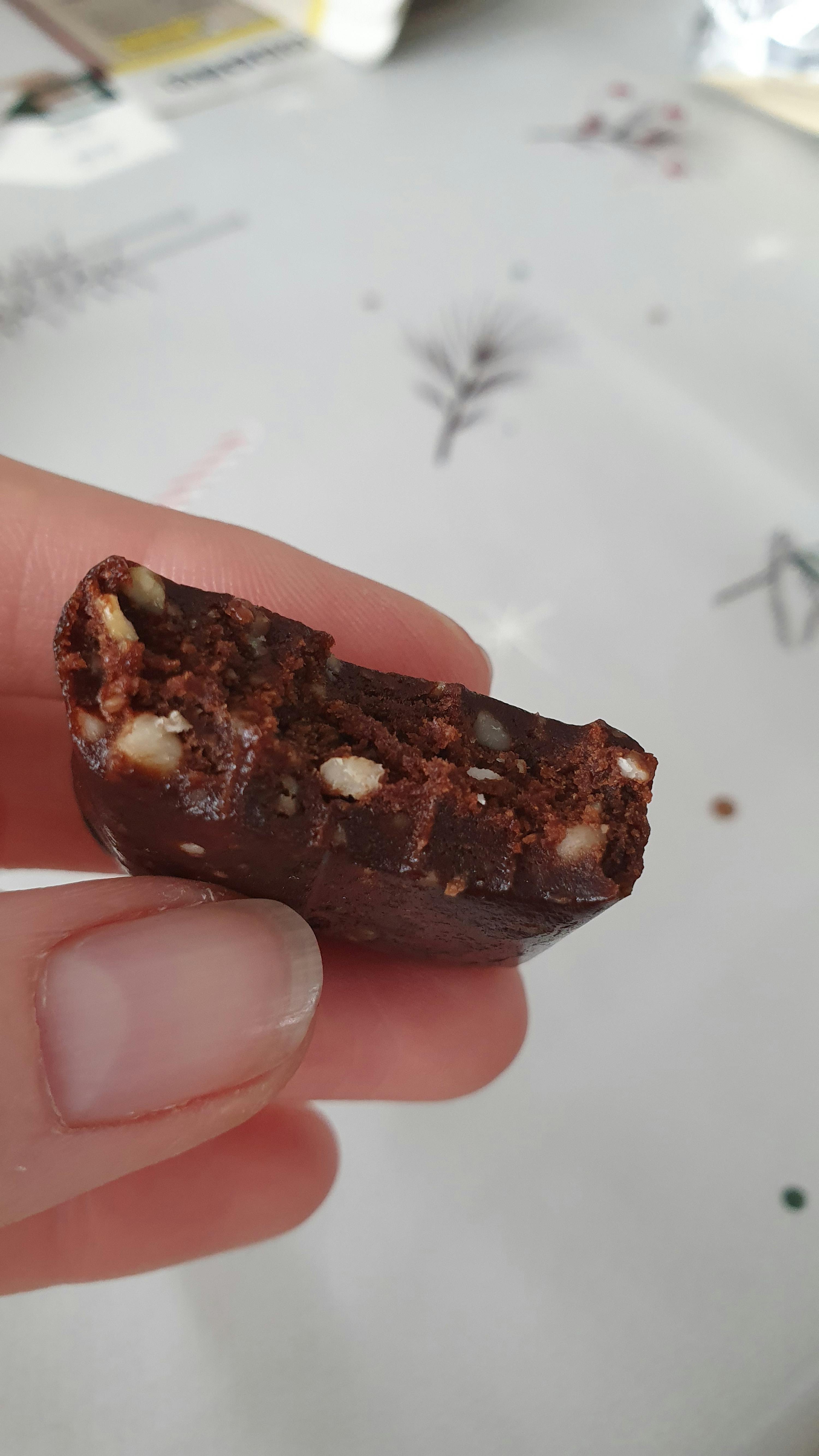 a person holding a piece of chocolate with nuts in it