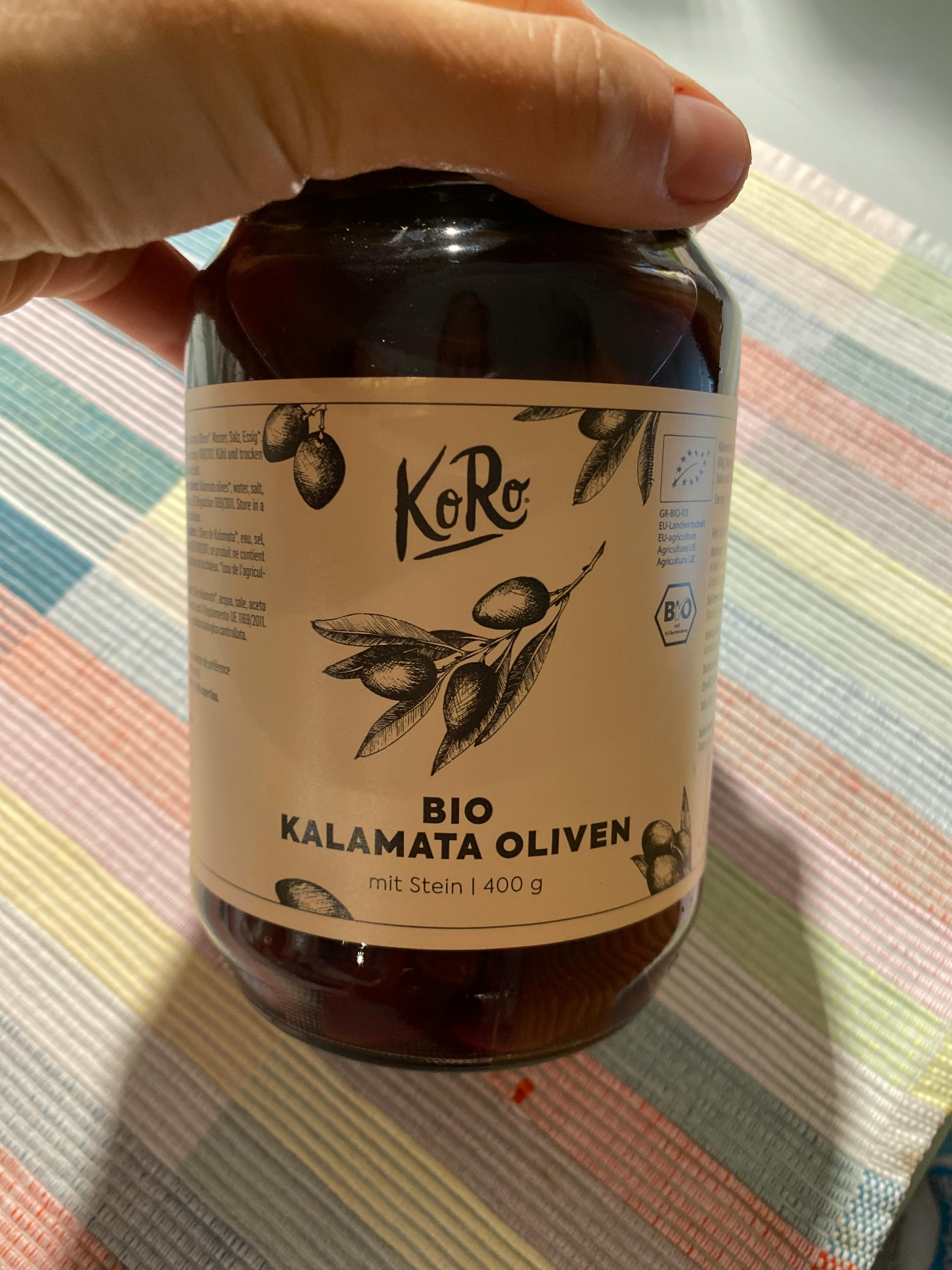 eine Person hält ein Glas Karamata Oliven in der Hand