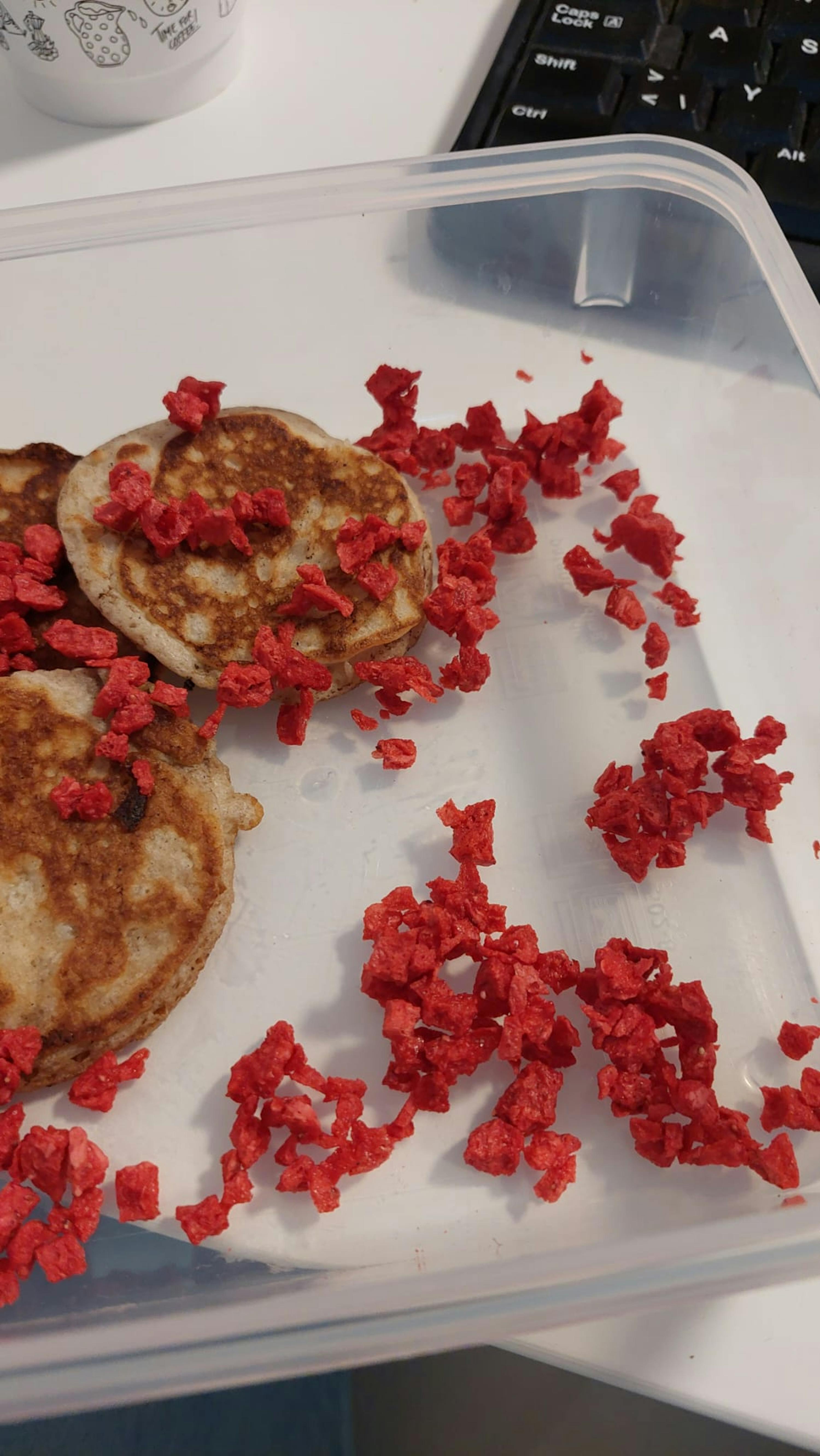 ein Plastikbehälter mit Pfannkuchen und cheerios auf einem Tisch